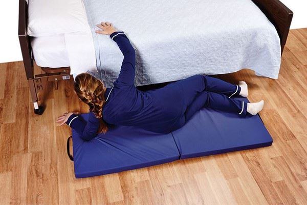patient lying on fall mat next to bed
