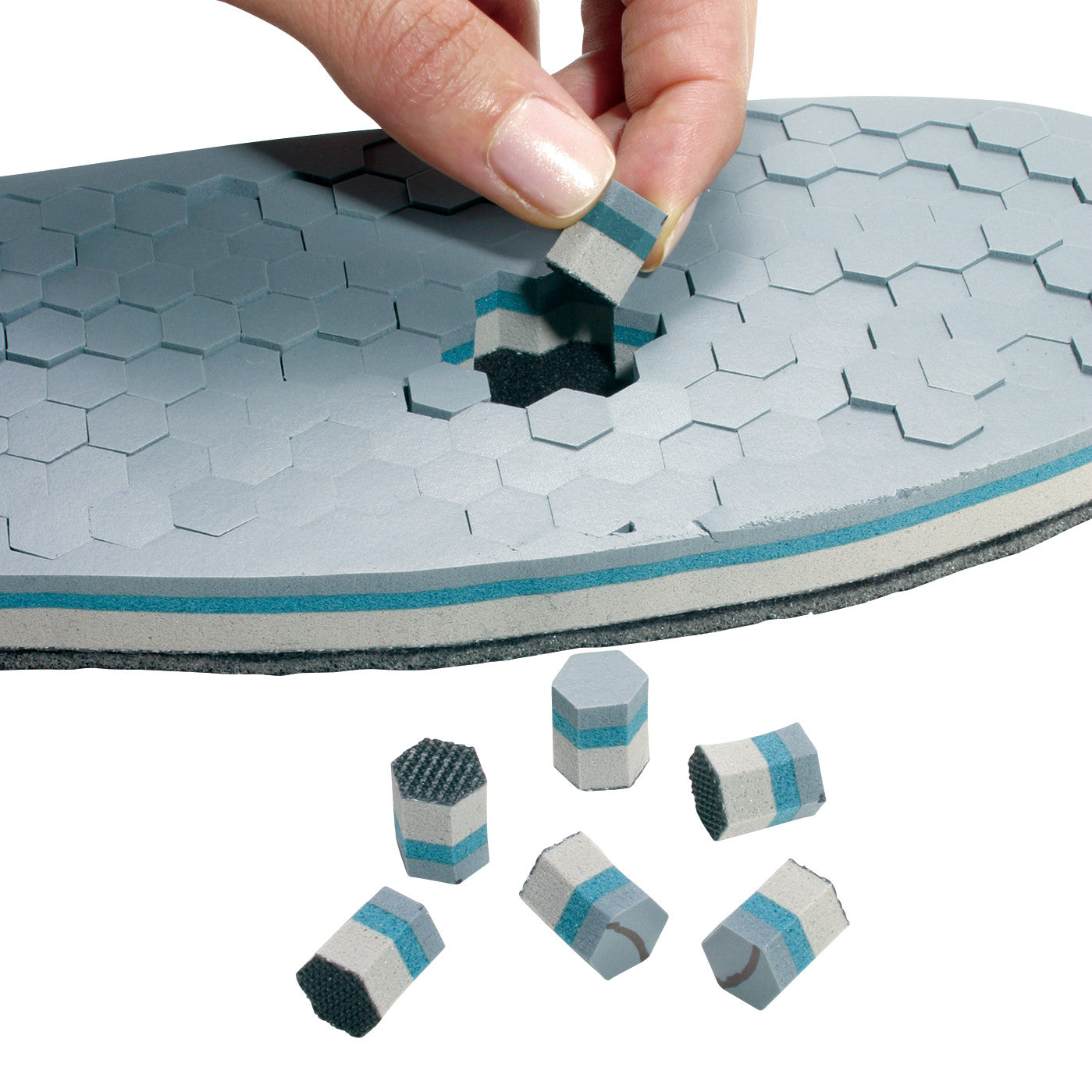 A hand removes hexagonal foam pieces from an ssur DH Offloading Post-Op Shoe insole, designed for pressure relief and comfort.