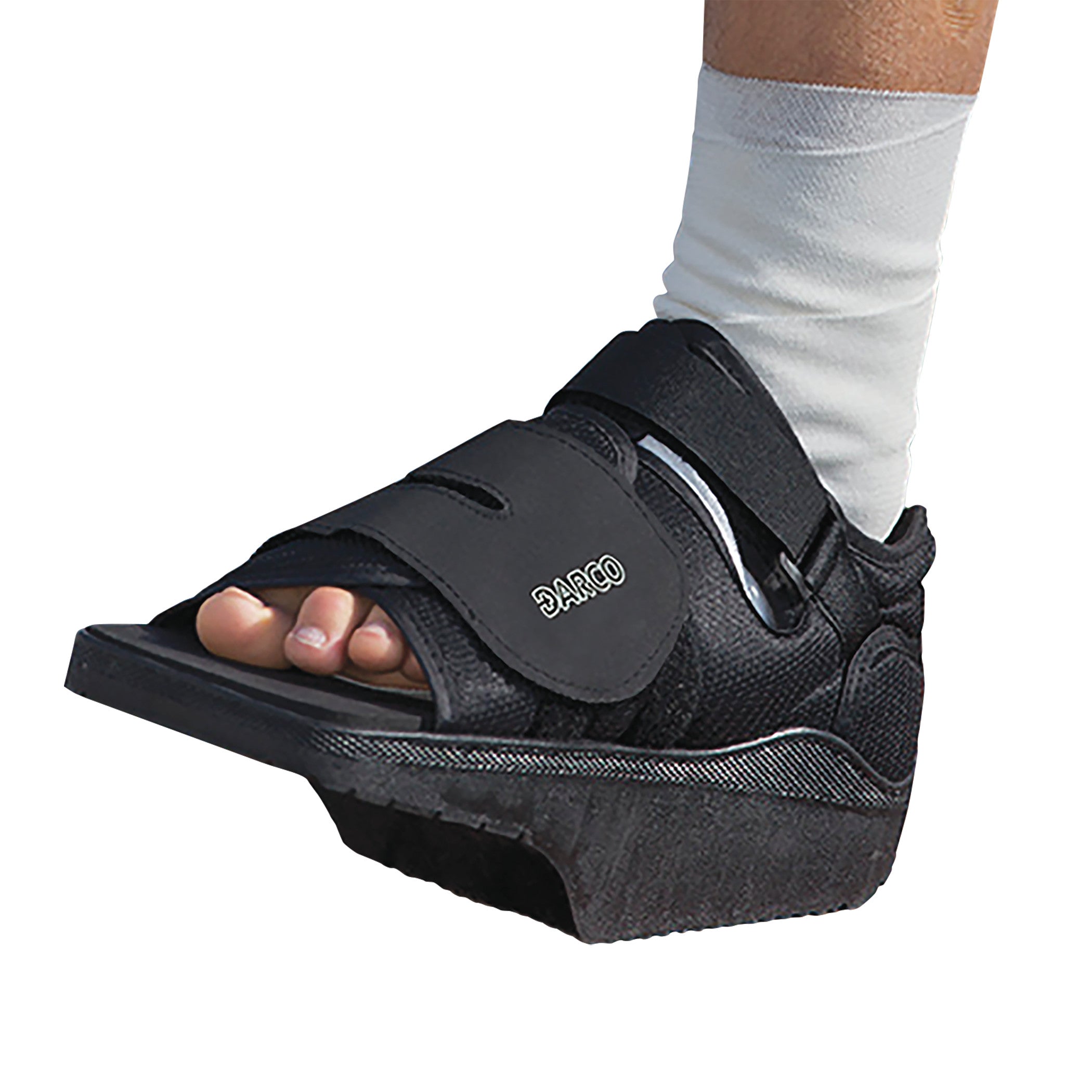 A foot wearing a DARCO OrthoWedge Shoe, featuring a black open-toe design with adjustable straps and a wedge-shaped sole.