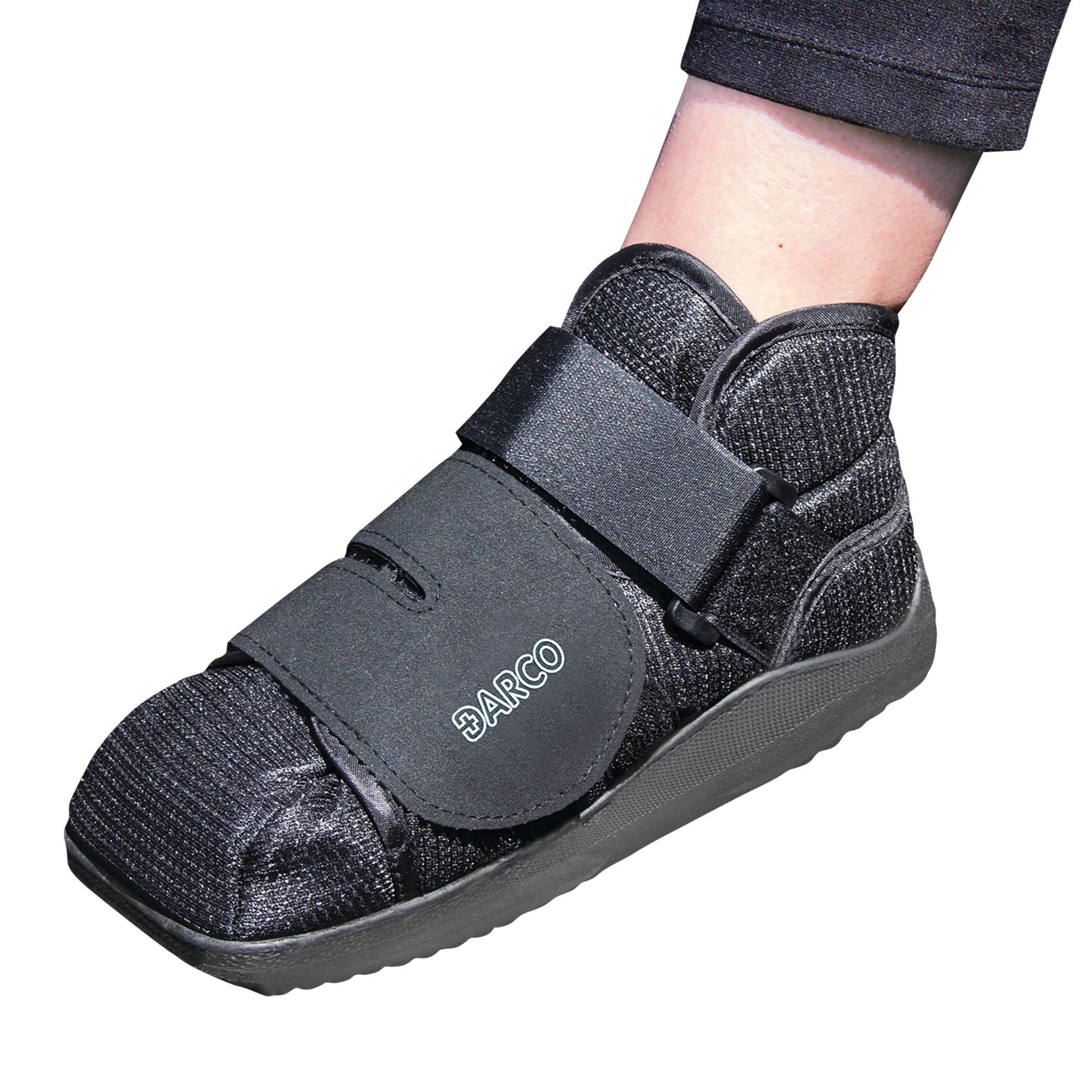 A person wearing a black DARCO APB Shoe with adjustable straps and a textured sole for support and protection.
