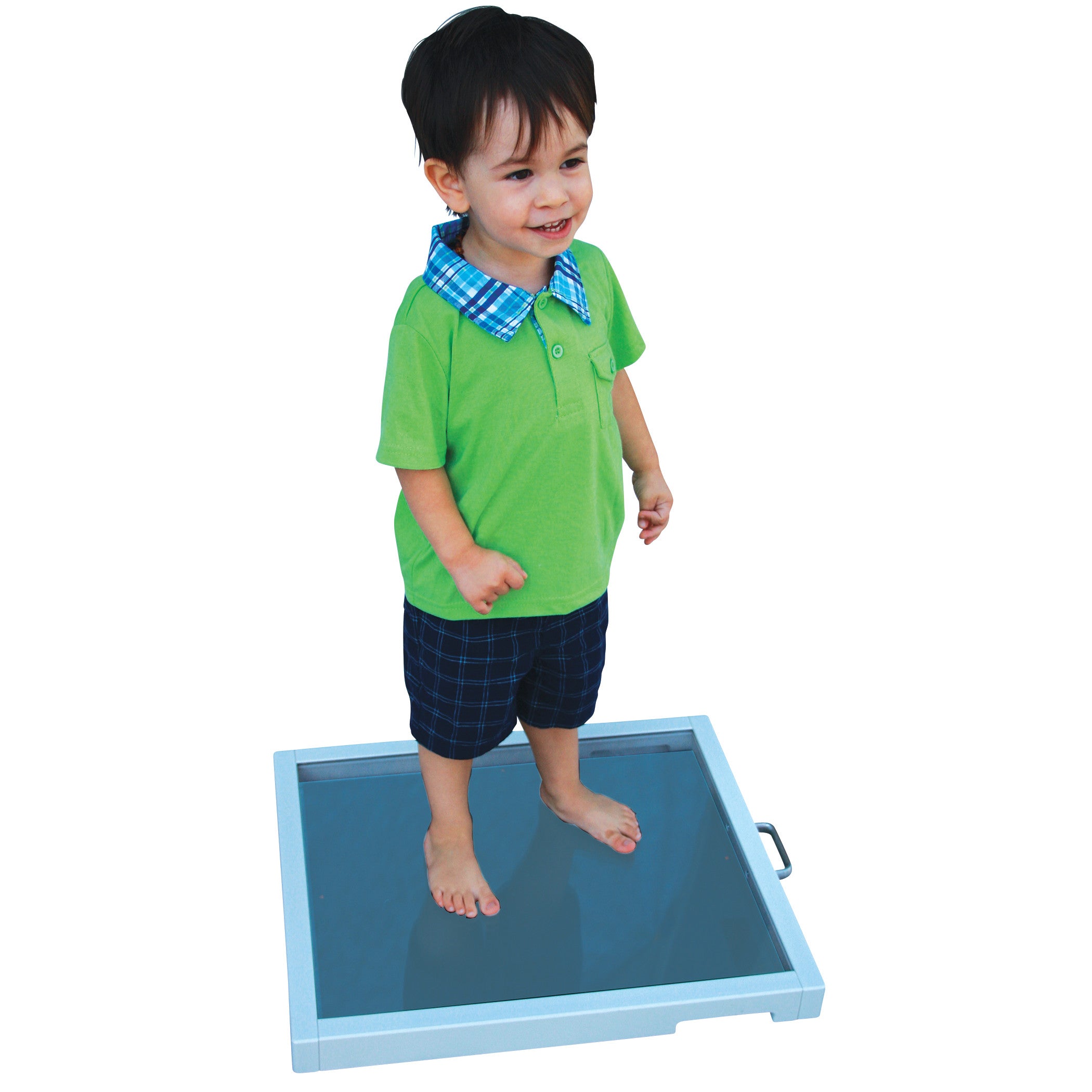 A young child stands barefoot on a Film/Cassette Protector, smiling. The protector is a flat, rectangular platform with a handle.