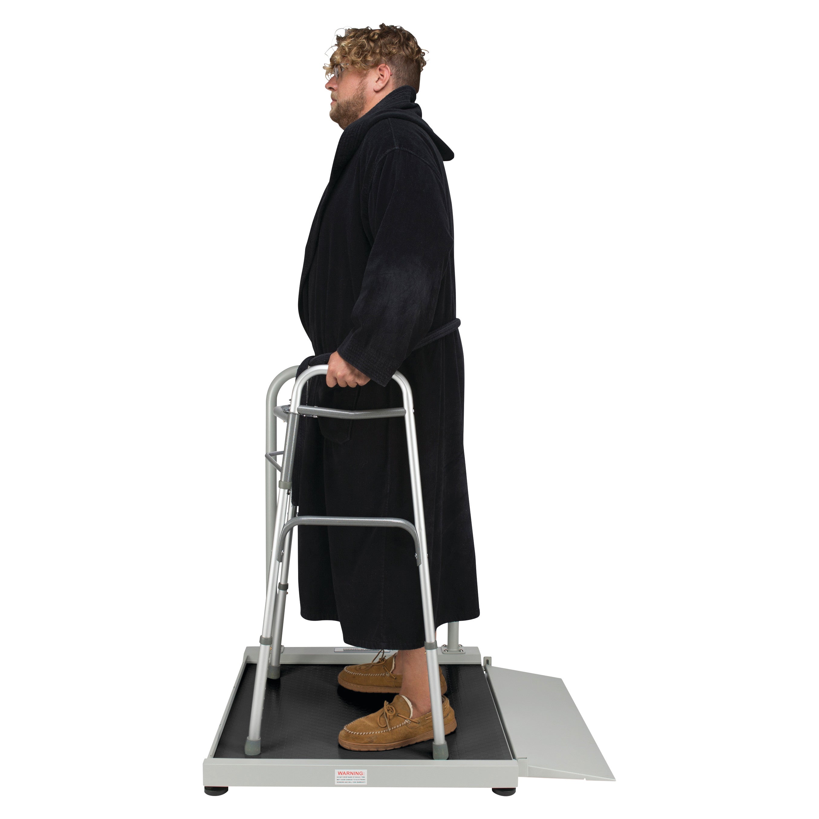 A person stands on the Health o meter Digital Wheelchair Ramp Scale with Everlock, using a walker, wearing a black robe.