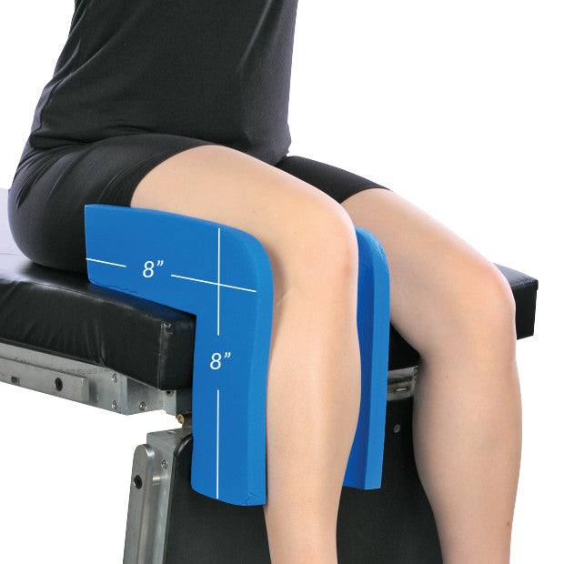 A person is seated, using the AliMed Vinyl-Coated Well-Leg Holder on an exam table, supporting their legs at an 8-inch height.