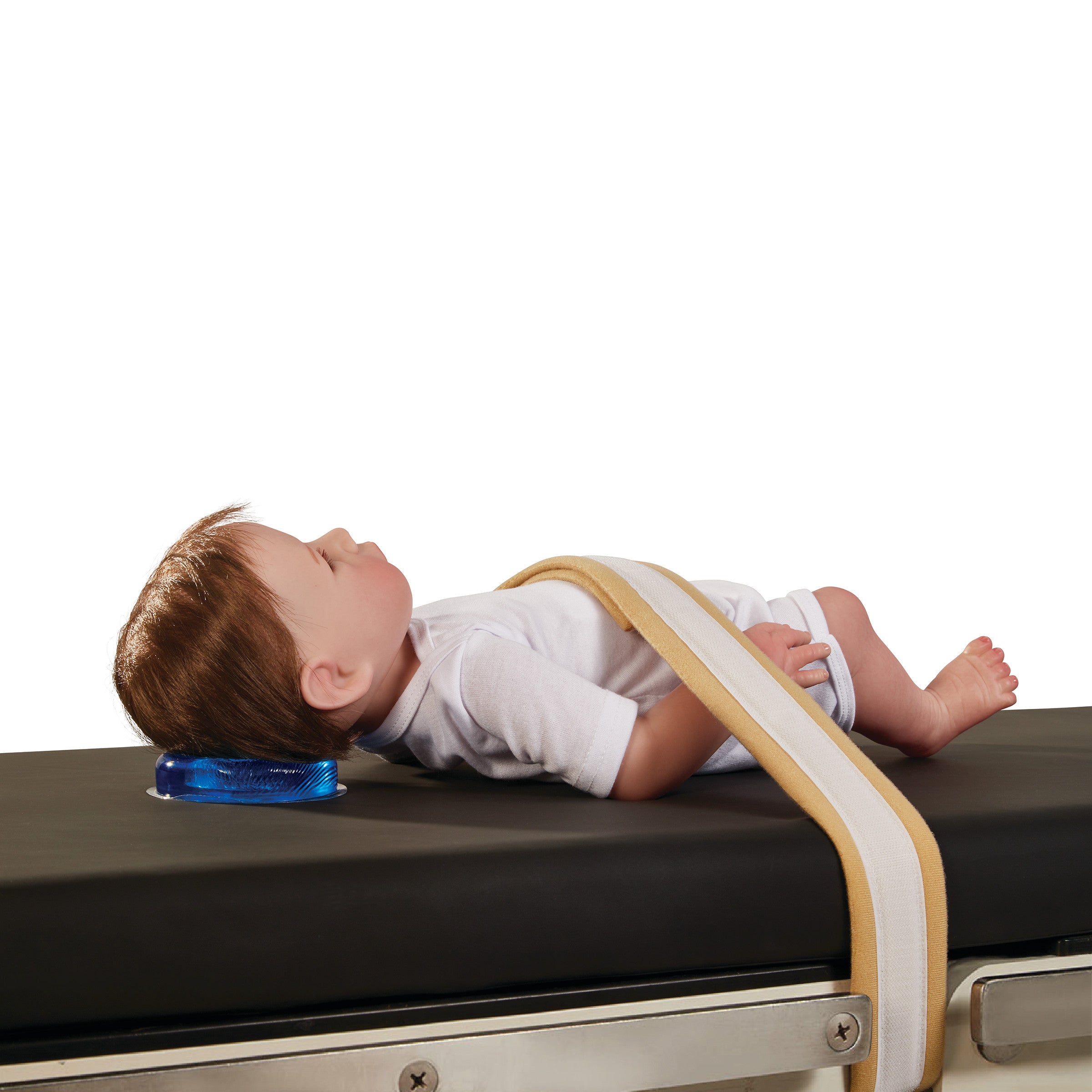 A doll is shown on a medical table with the AliMed AliBlue Gel Head Donut supporting its head. A strap secures the doll's abdomen.