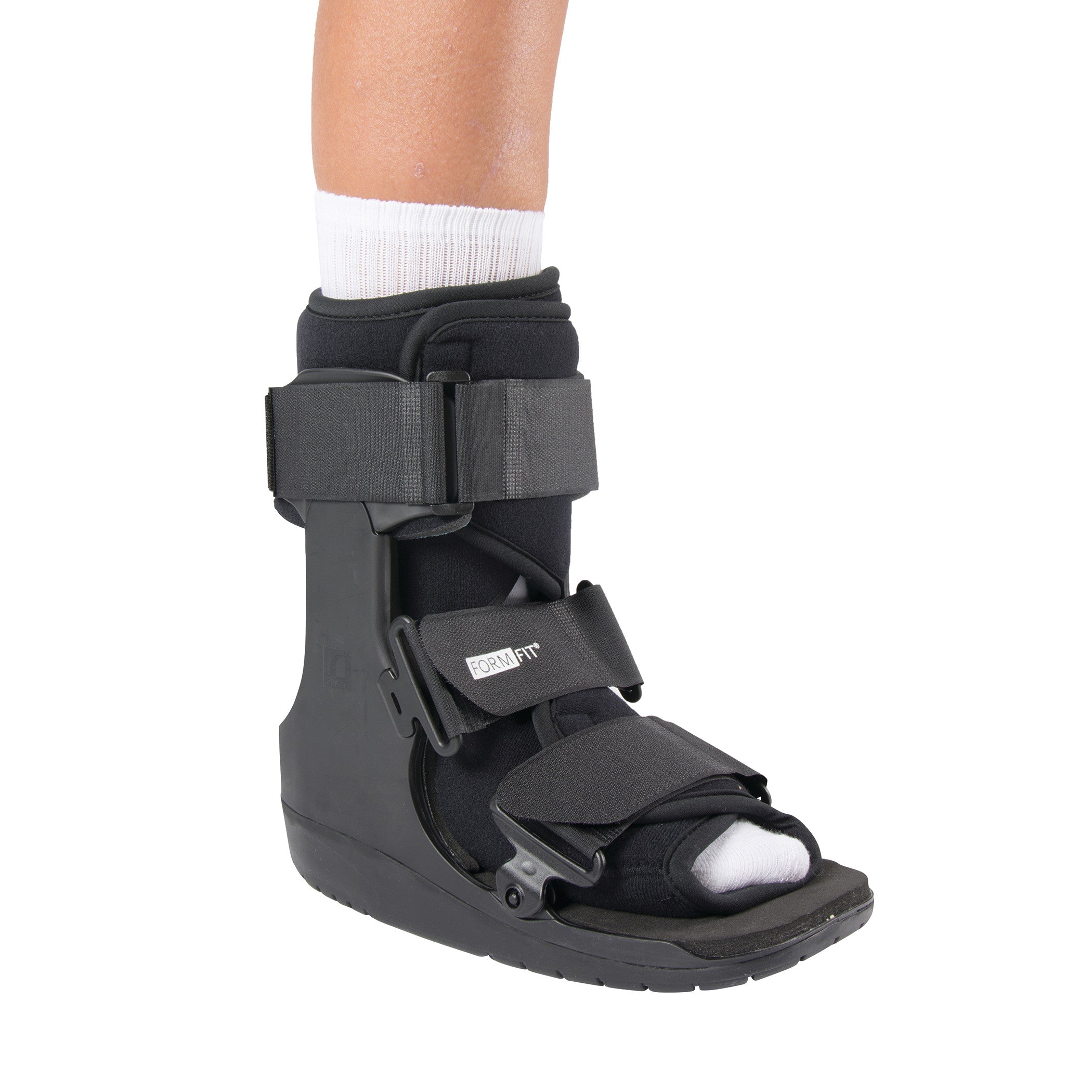 A person wearing an ssur Formfit Low-Top Walker boot, featuring black straps and an open-toe design for foot support.