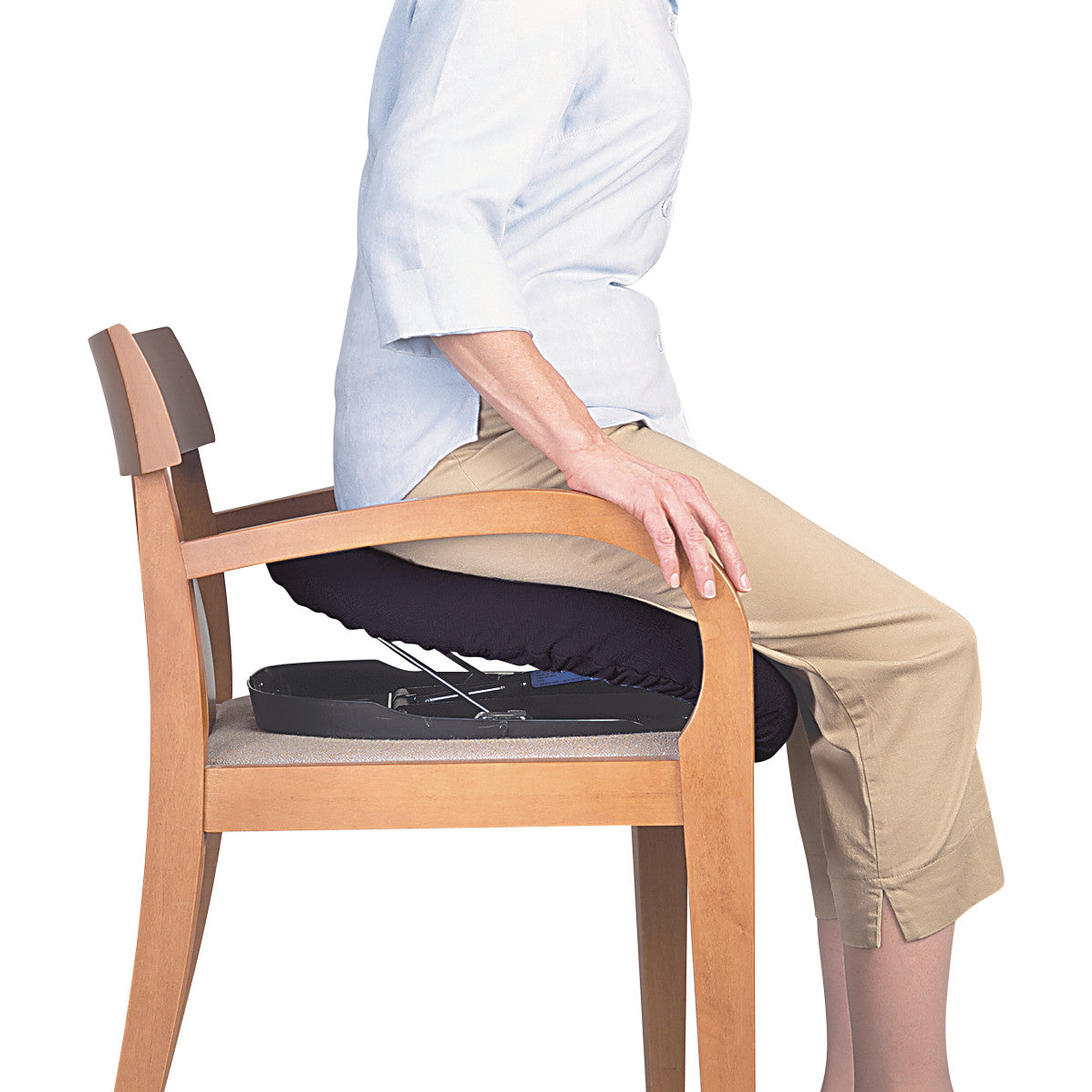 A person demonstrates the use of the Carex Uplift Seat Assist on a wooden chair, showing how it helps in sitting and standing.