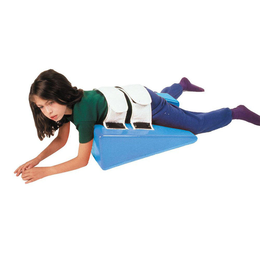 A child lies on a blue Skillbuilders Strap Wedge, secured with white straps, positioned for support and alignment.