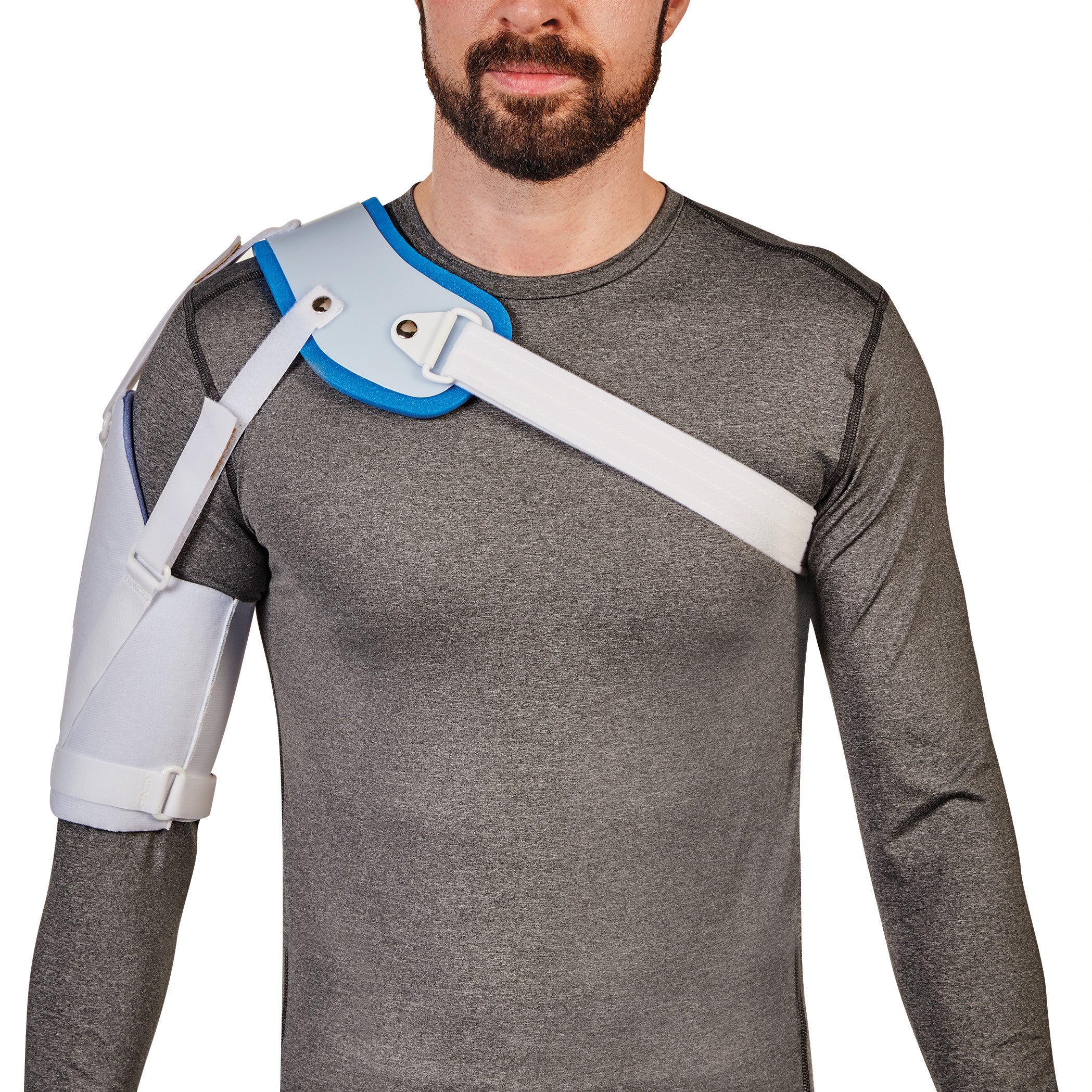 A man wears an AliMed Hemi-Shoulder Sling over a gray shirt, featuring white straps and blue padding for shoulder support.