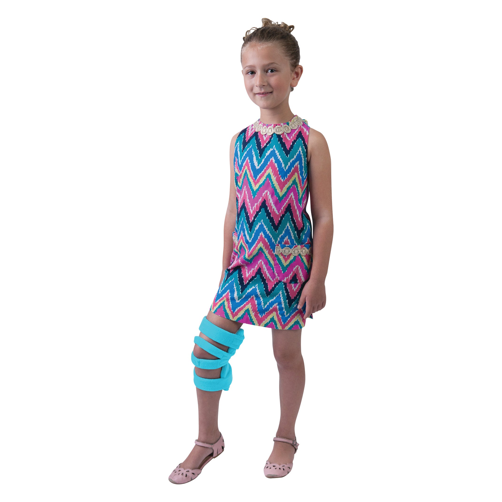 A child wears the Comfy Splints Pediatric Goniometer Knee Orthosis with a zigzag dress. The knee brace is bright blue.