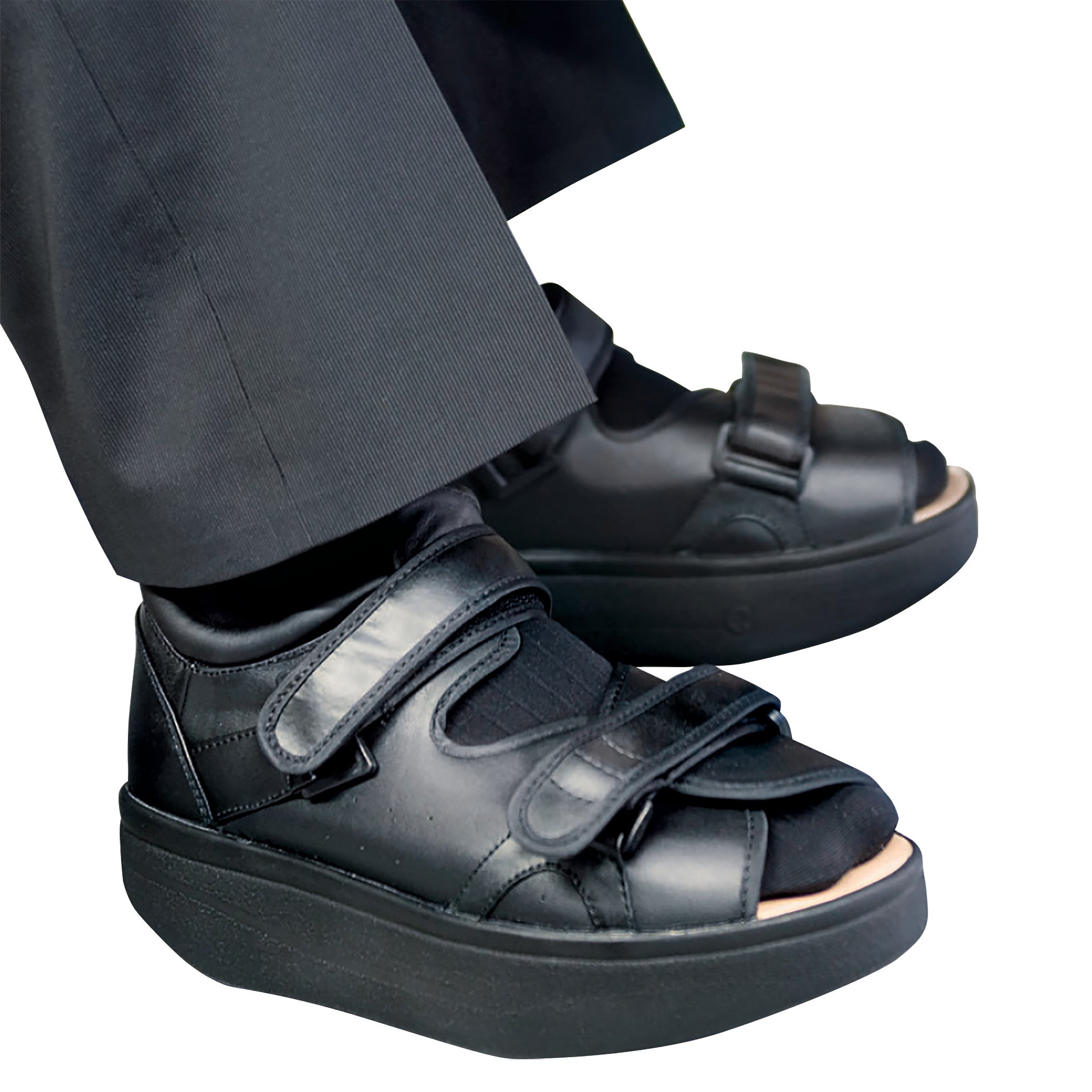 The DARCO Open Toe Wound Care Shoe System in black features straps, a thick sole, and is worn with black pants.