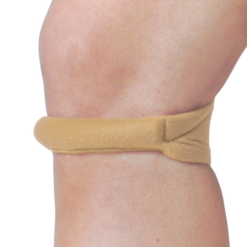 A Cho-Pat Knee Strap is wrapped around a knee, providing support. The strap is beige and designed for pain relief and stability.