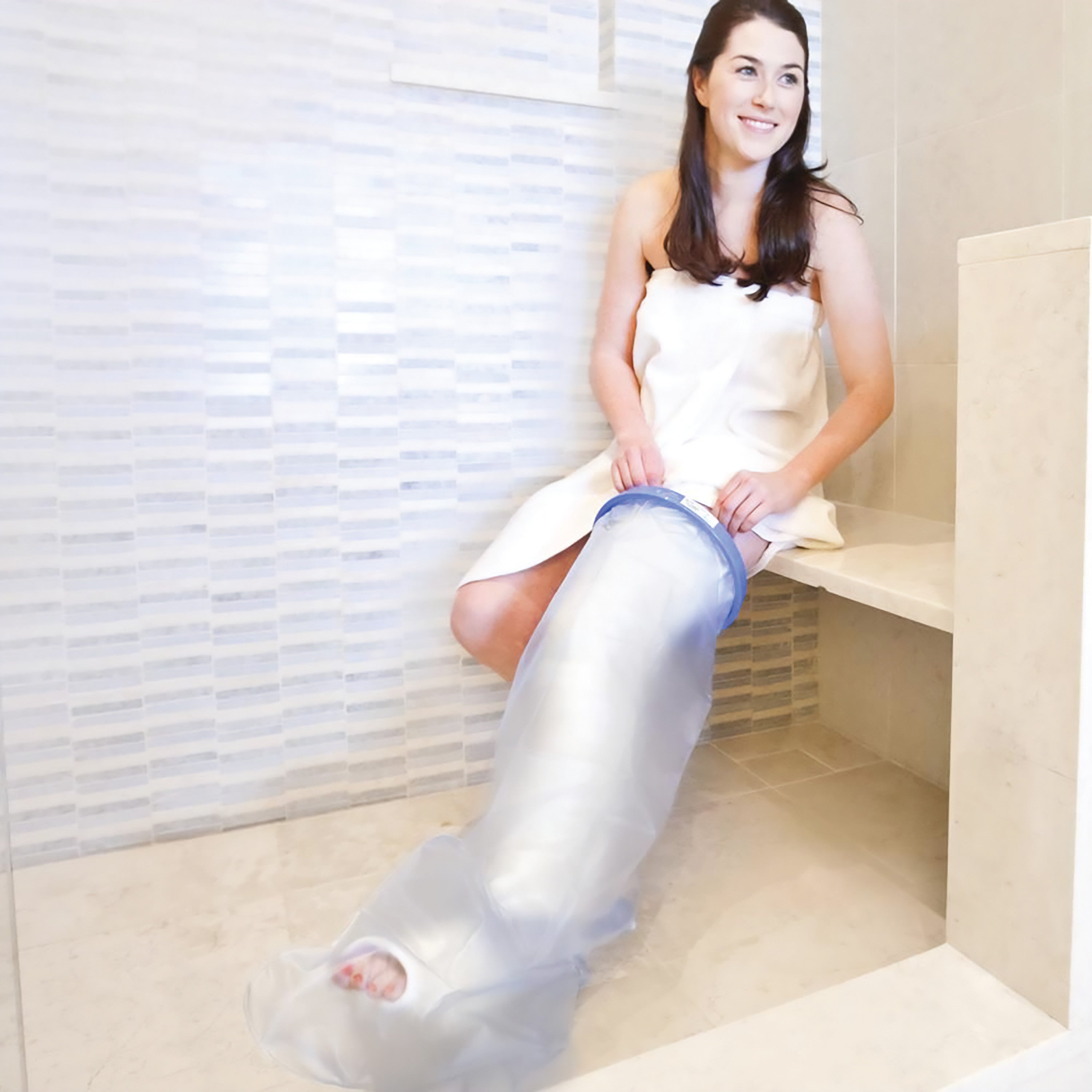 A person uses the Brownmed SEAL-TIGHT Original Cast and Bandage Protector on their leg while seated in a tiled shower area.