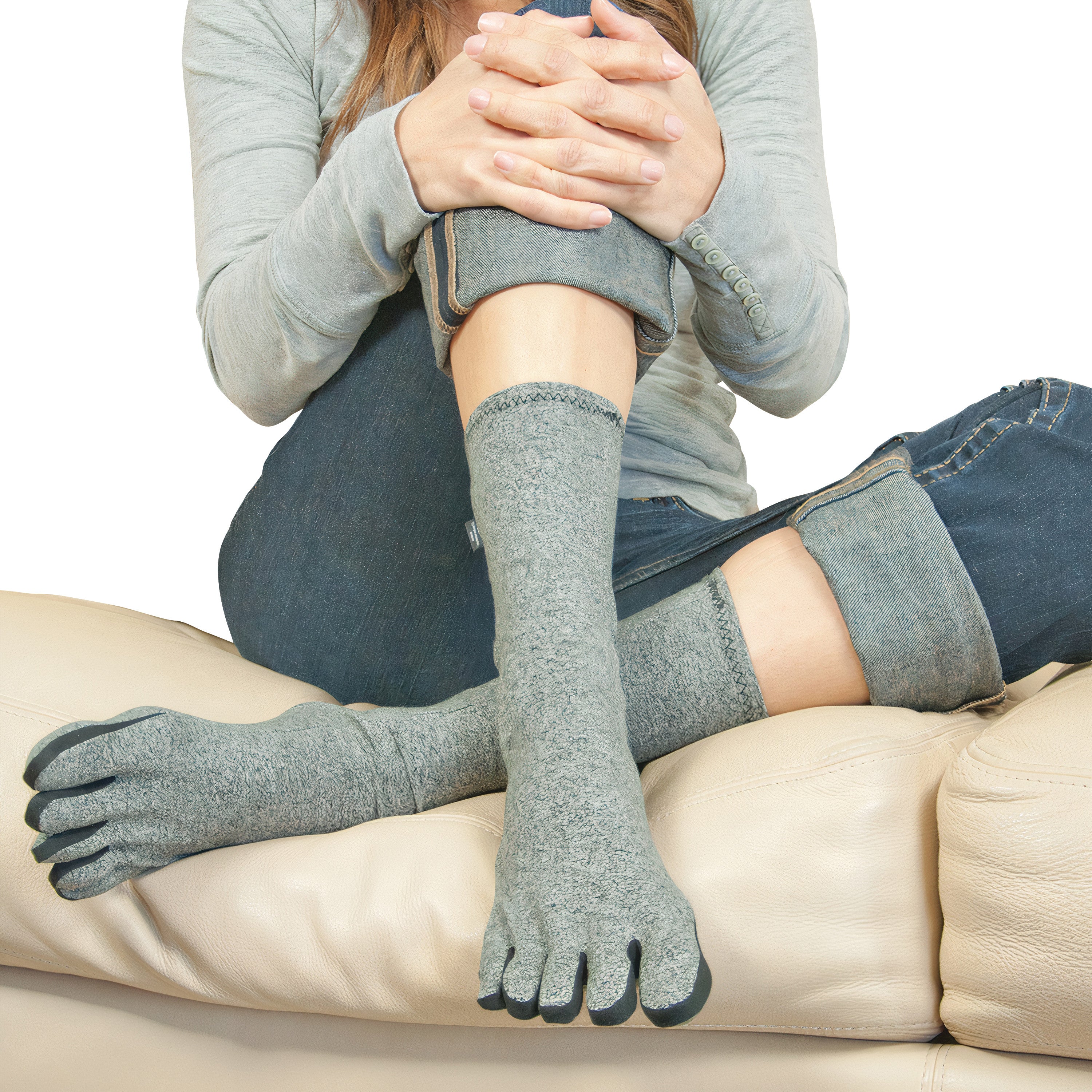 A person wearing Brownmed IMAK Compression Arthritis Socks sits on a couch with legs crossed, showcasing the socks' toe design.