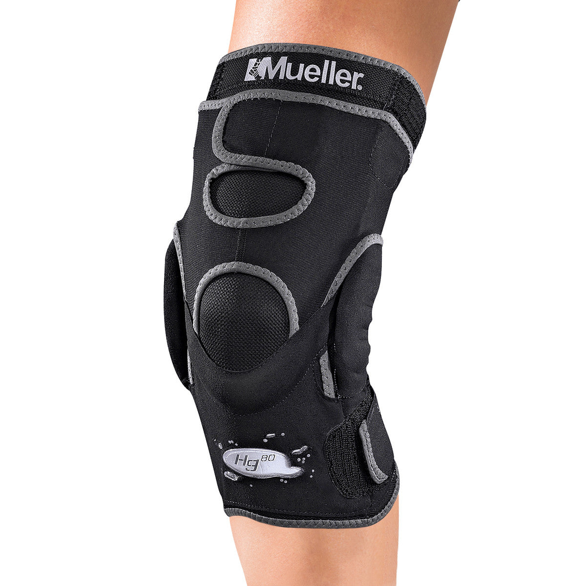A person wears a Mueller Hg80 Knee Brace, featuring black fabric with gray trim and cutouts for flexibility and support.