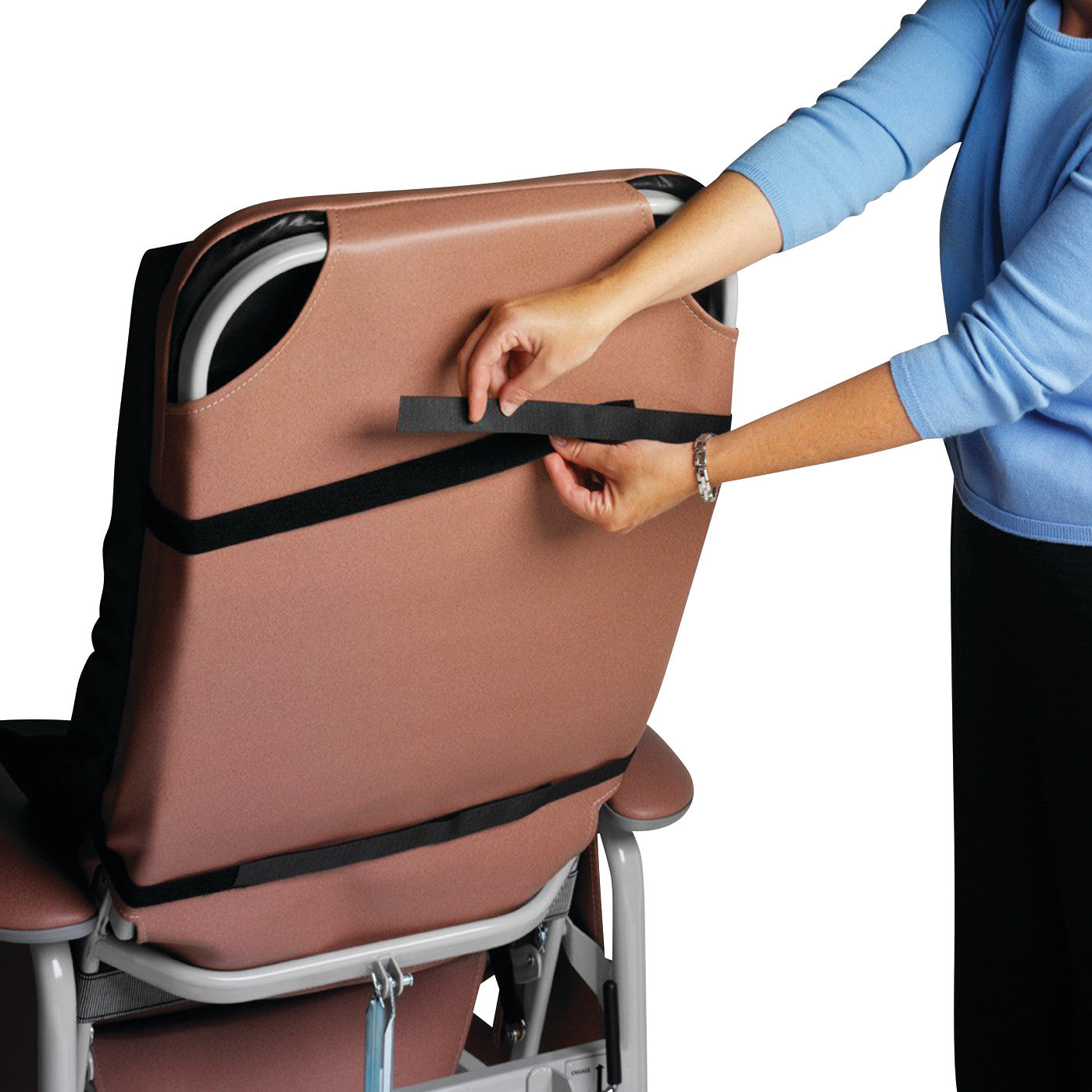 A person attaches a strap to a Geo-Wave Specialty Recliner Cushion, which is fitted to a brown recliner chair.