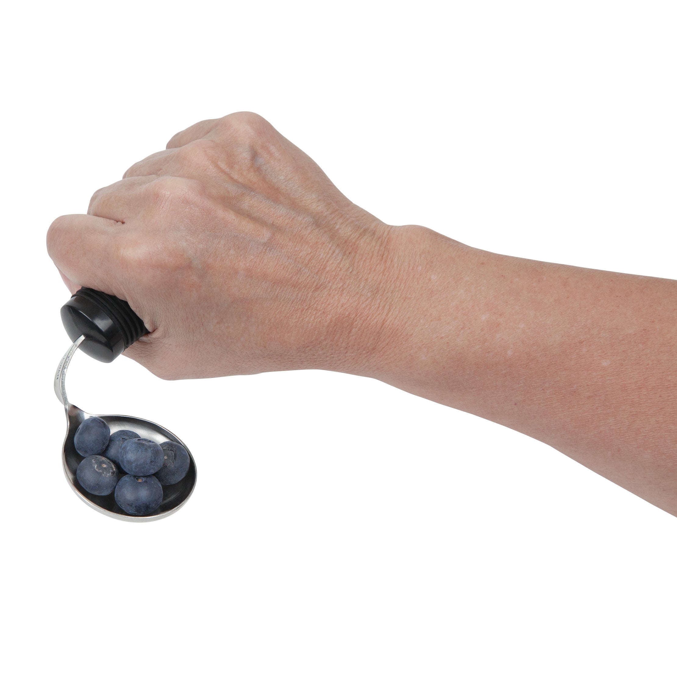 A hand holds a Good Grips Standard Utensil spoon with a black handle and blueberries in the bowl.