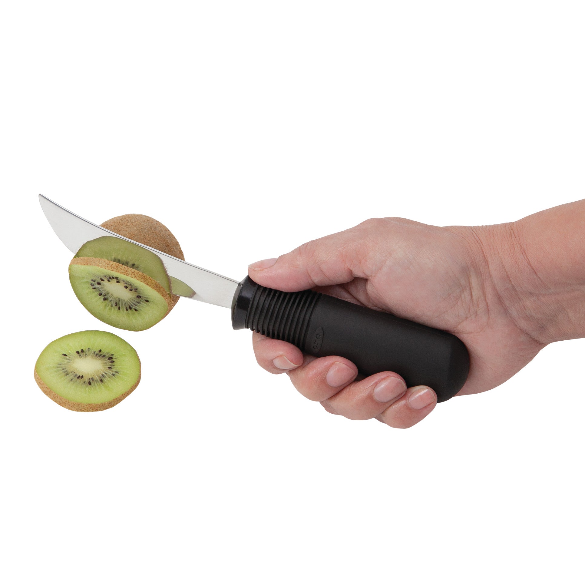 A hand holds a Good Grips Standard Utensils knife slicing a kiwi. The knife has a black ergonomic handle.