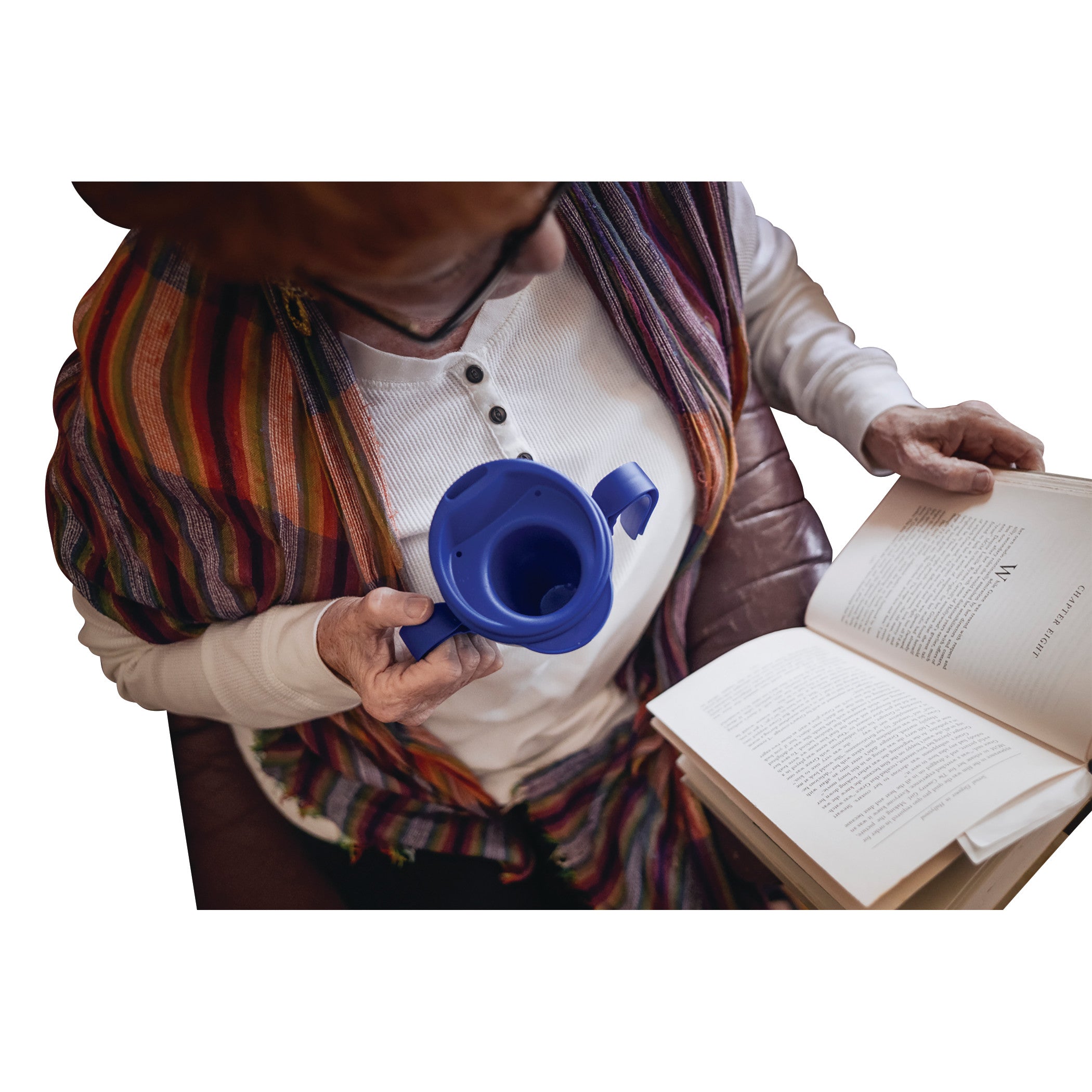 Person reading and holding a blue Provale Cup designed for controlled sips. The person wears a striped shawl and white shirt.