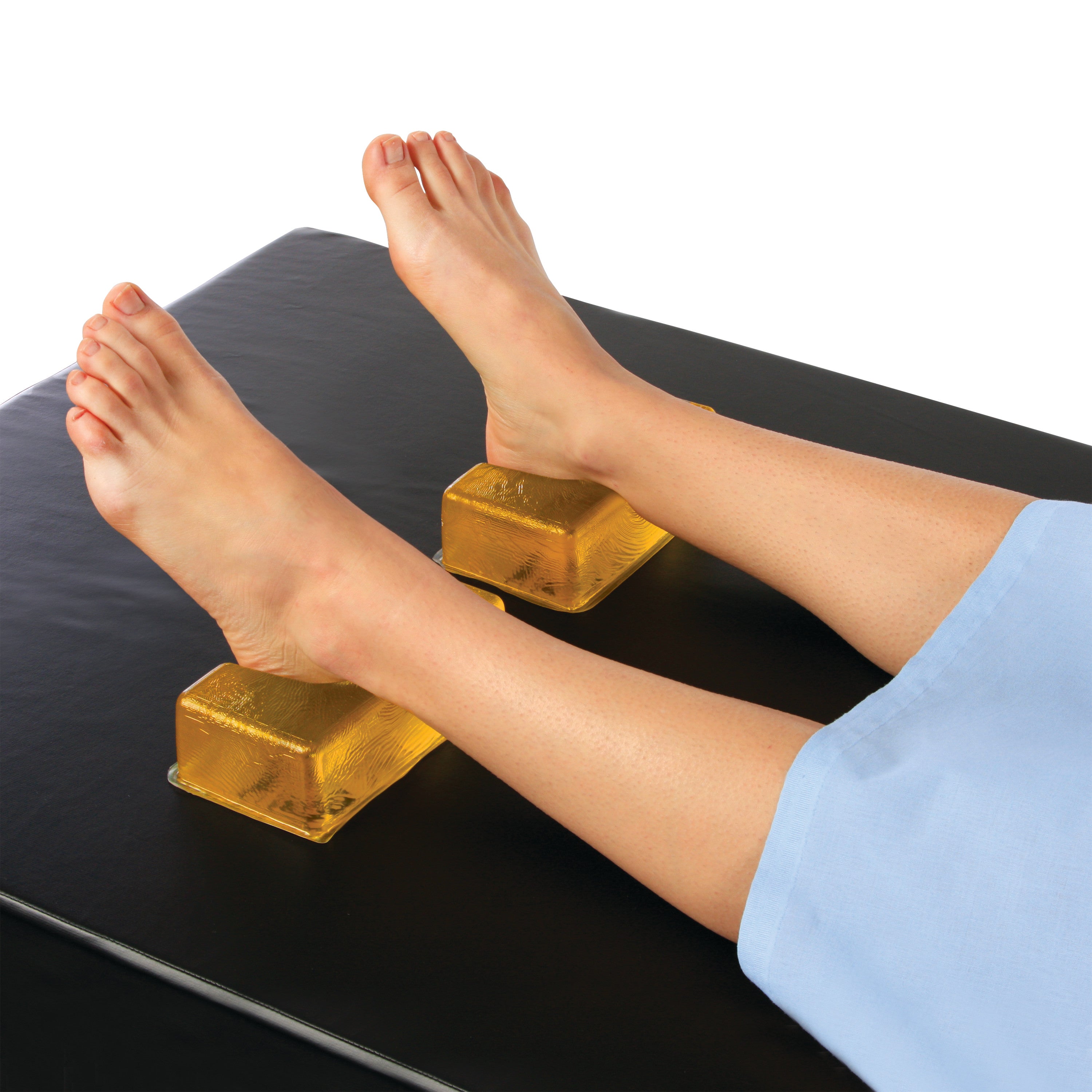 Feet resting on AliMed AliGel Heel Cups, which are yellow and placed on a black surface, covered by a blue cloth.