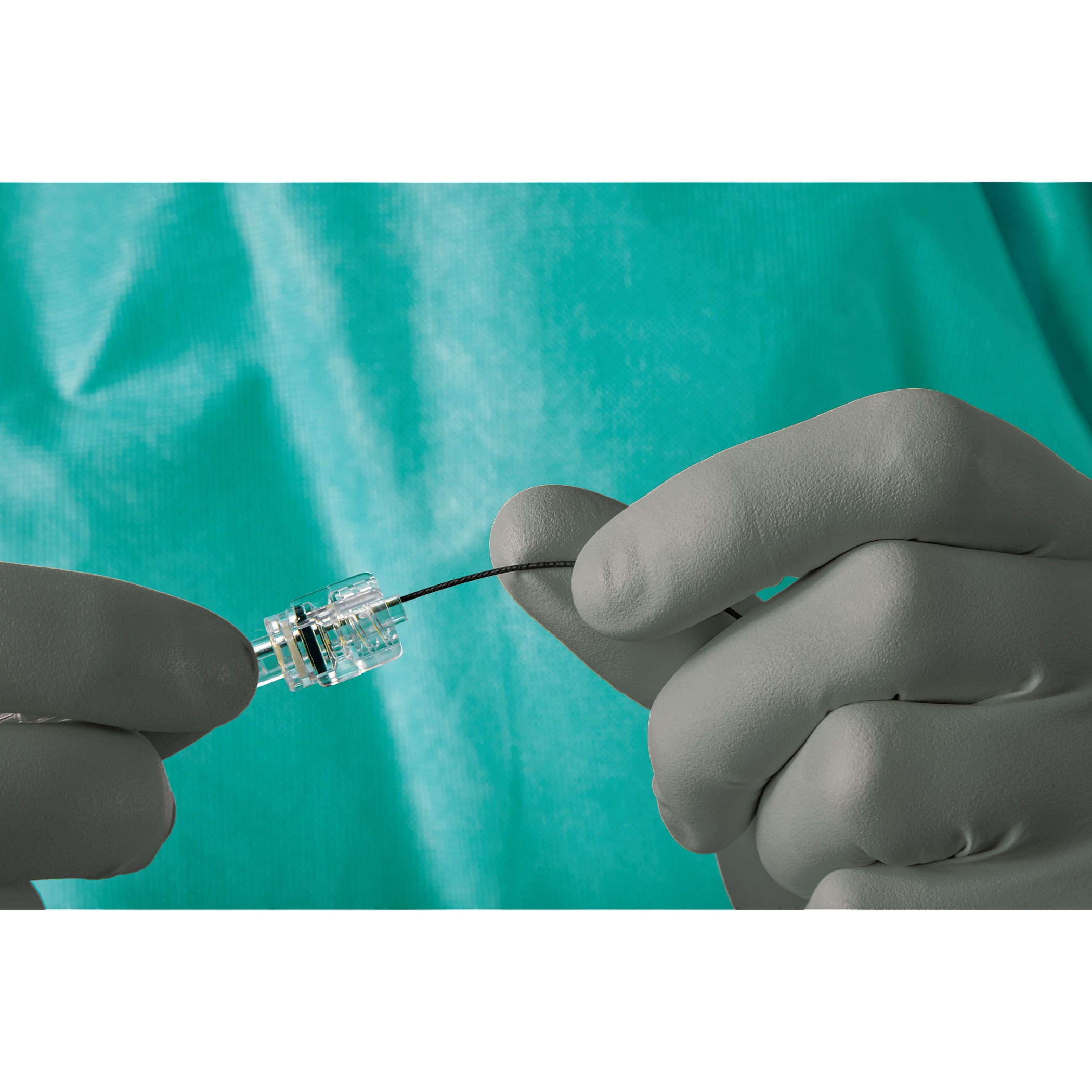 A person wearing AliMed AliGuard Radiation Attenuation Gloves holds a small medical instrument against a turquoise background.