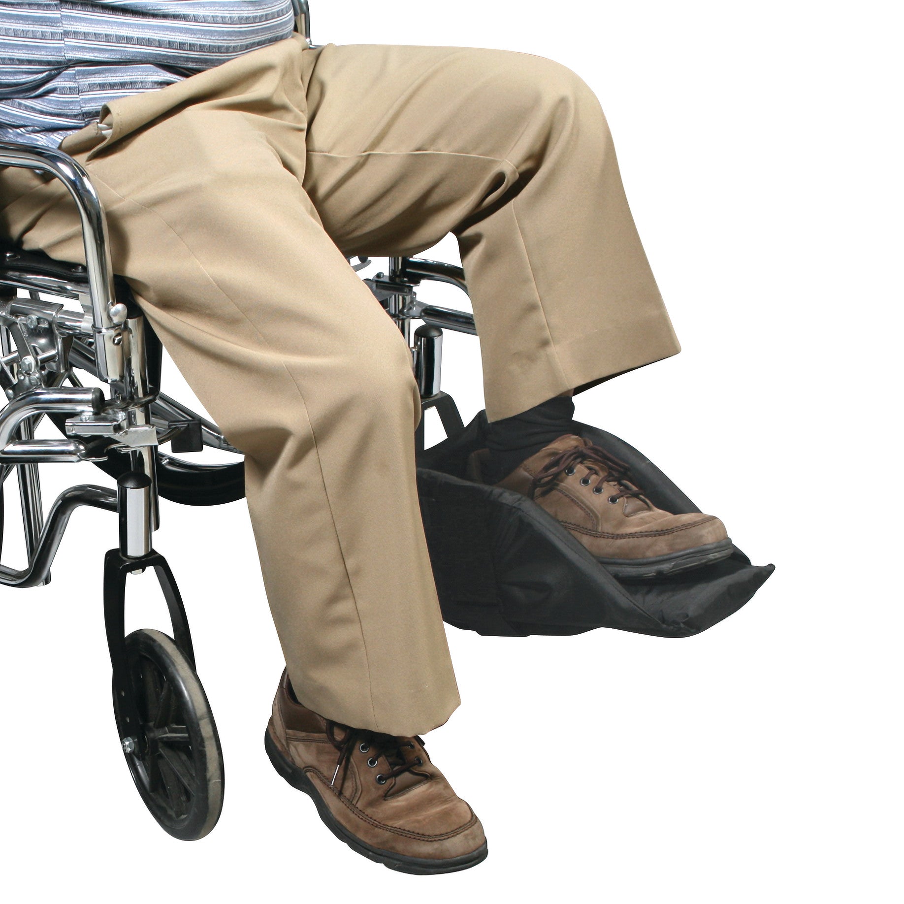 A person in a wheelchair uses the SkiL-Care Swing-Away Foot Support, wearing tan pants and brown shoes.