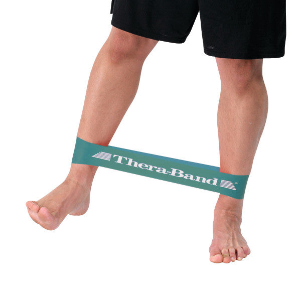 Person using a THERABAND Resistance Band Loop around ankles, stretching it with their legs apart while standing.