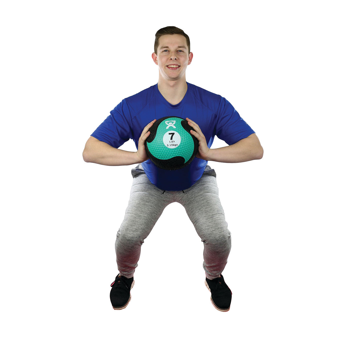 A person holds a green and black CanDo Rubber Medicine Ball labeled "7 lbs" while performing a squat.
