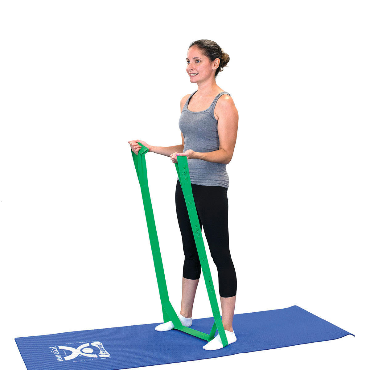 A person uses a green CanDo Multi-Grip Exerciser on a blue mat, holding the band while performing a standing exercise.