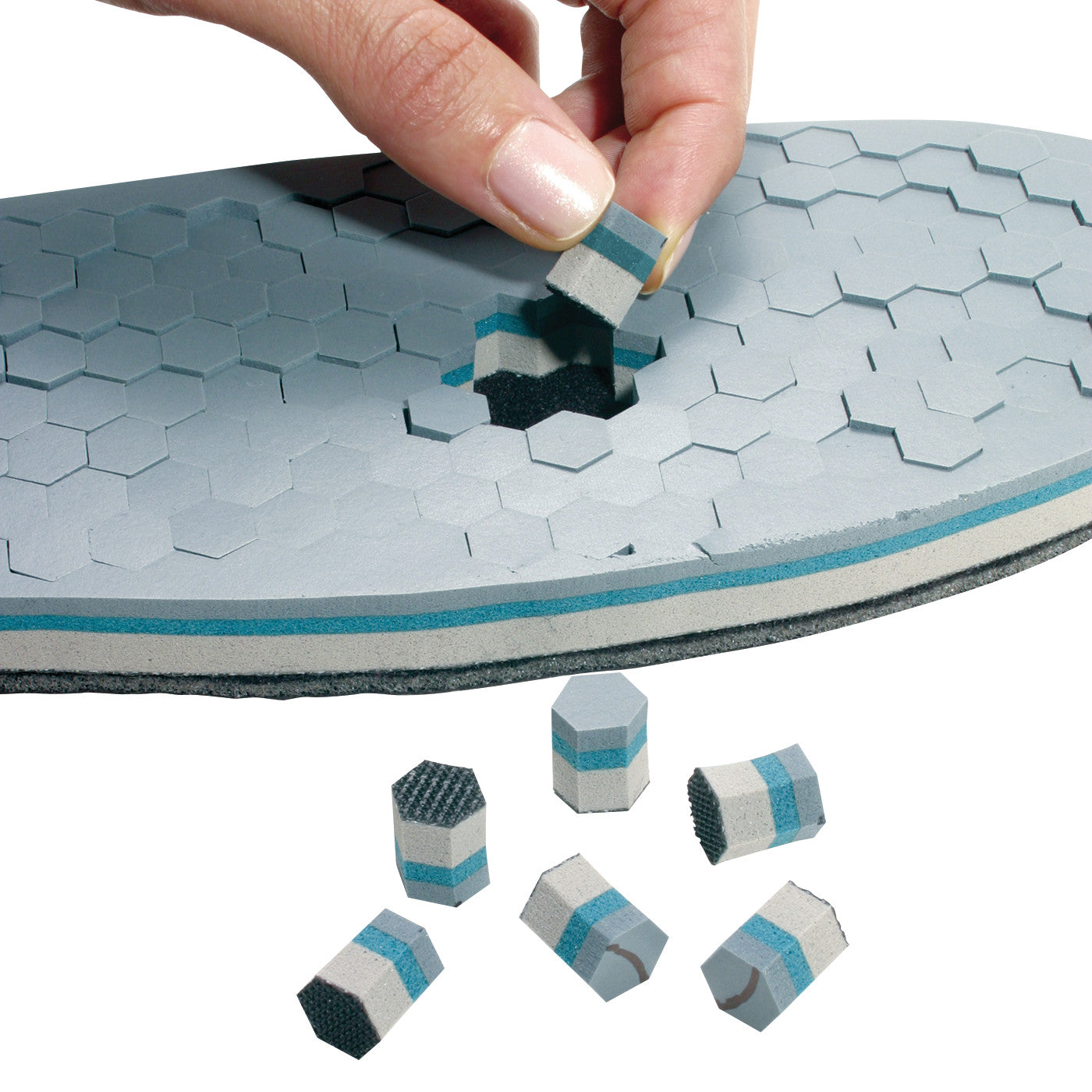 A hand removes a hexagonal block from an �ssur DH Offloading Walker insole, with several similar blocks scattered nearby.