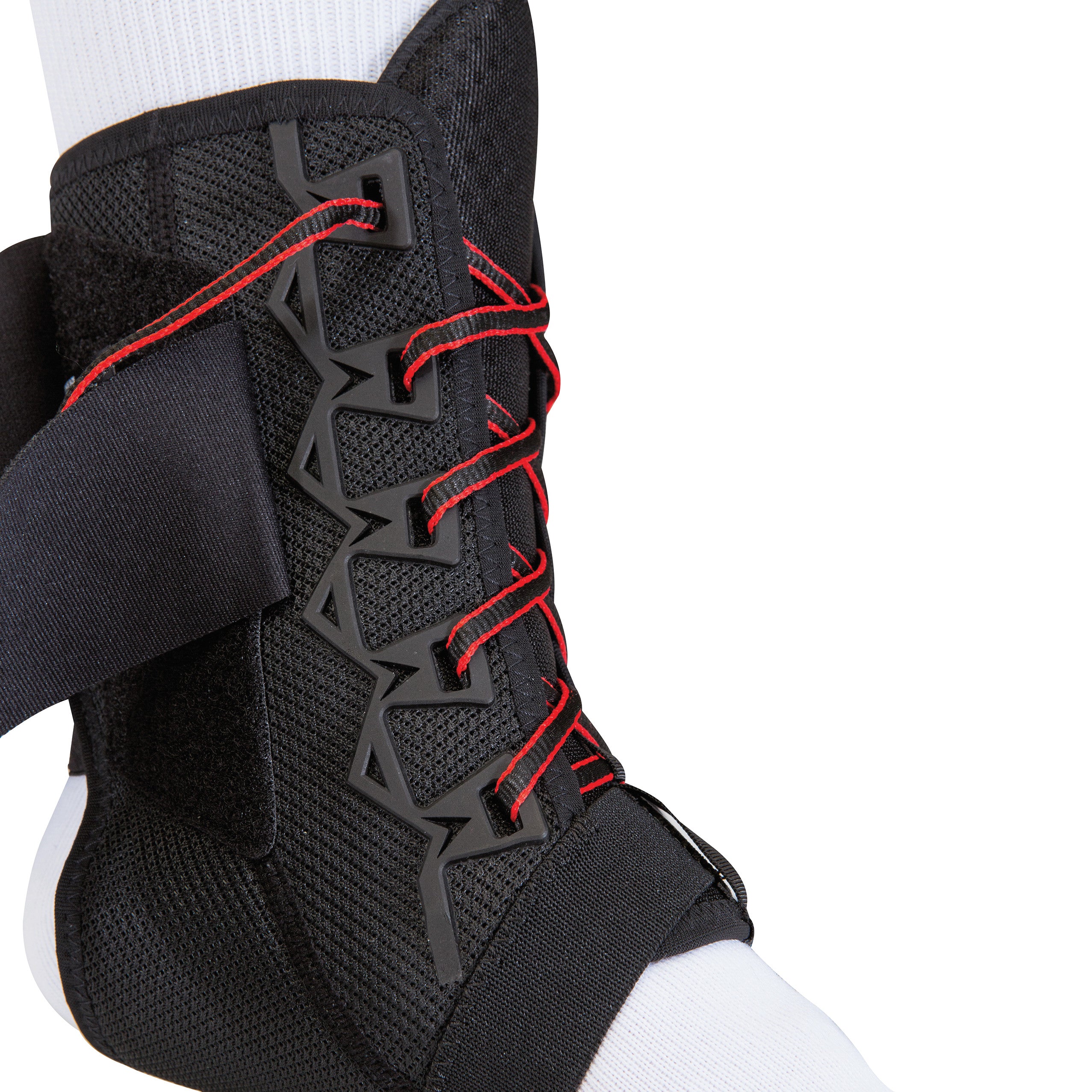 A foot wearing a Mueller The One Ankle Brace with black and red laces for support, over a white sock.
