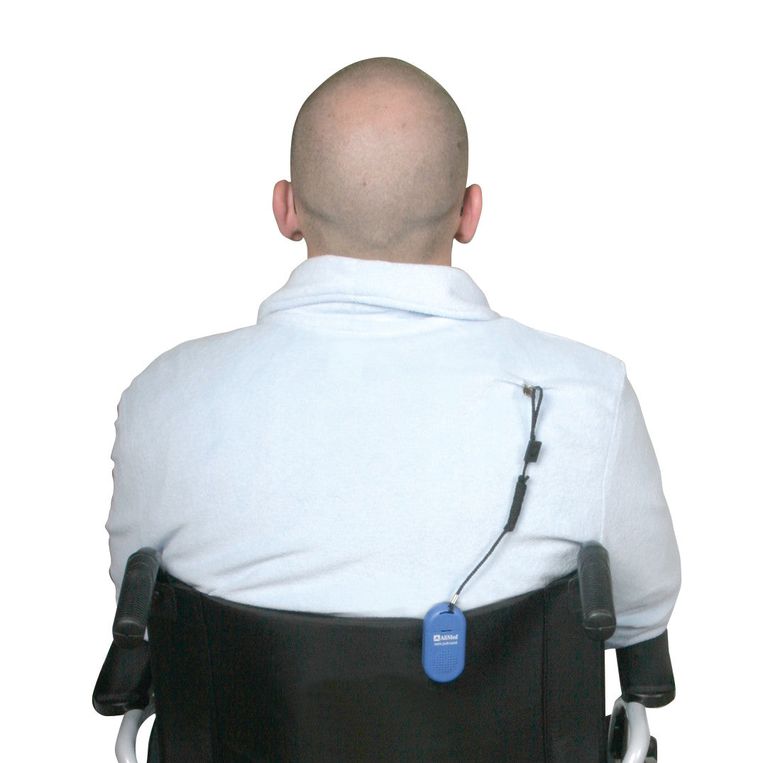 A person in a wheelchair with the AliMed Worry-Free Pull-Cord Alarm attached to the back, featuring a blue device and black cord.