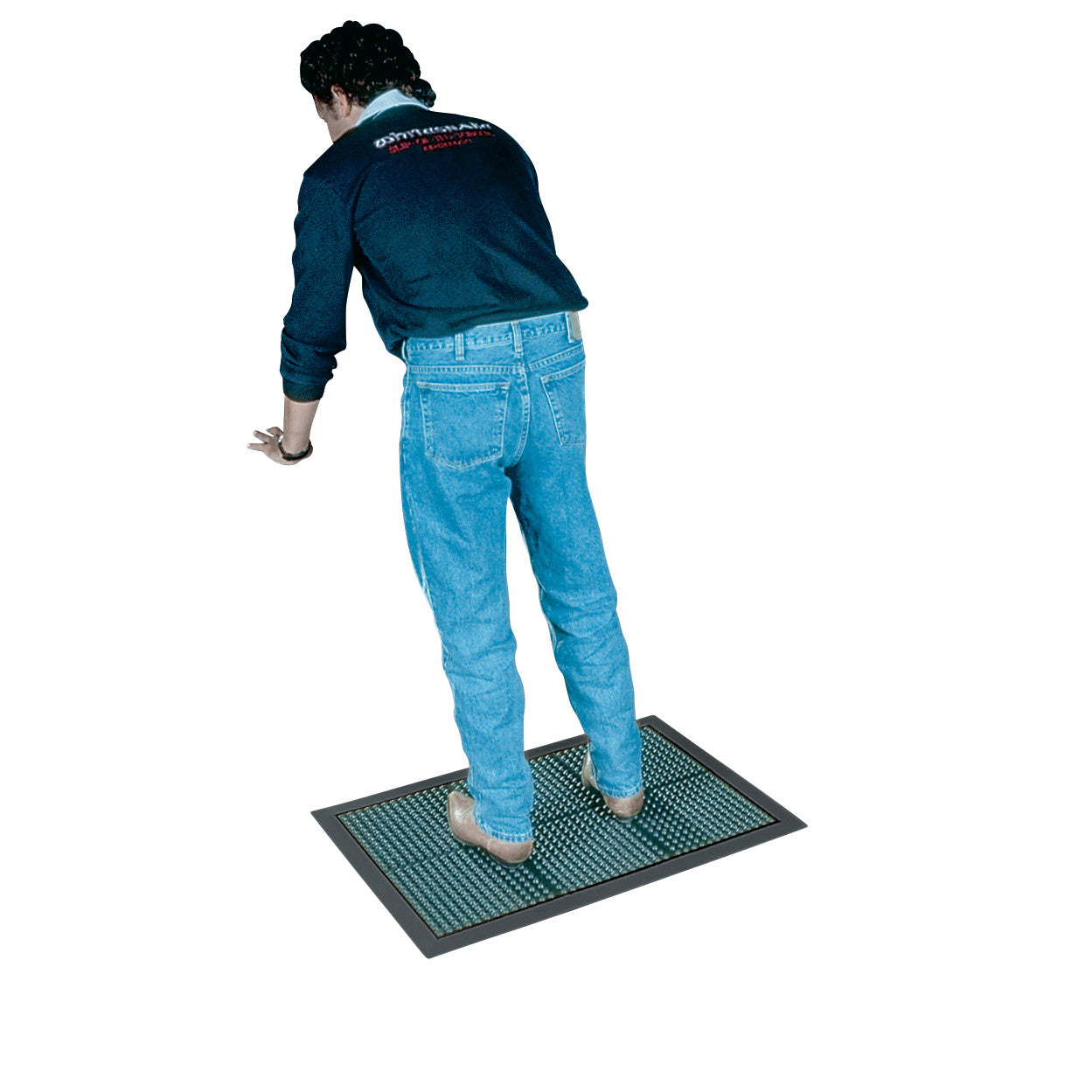 Person standing on a Wearwell Ortho Stand Anti-Fatigue Mat with a textured surface. The person wears jeans and a dark jacket.