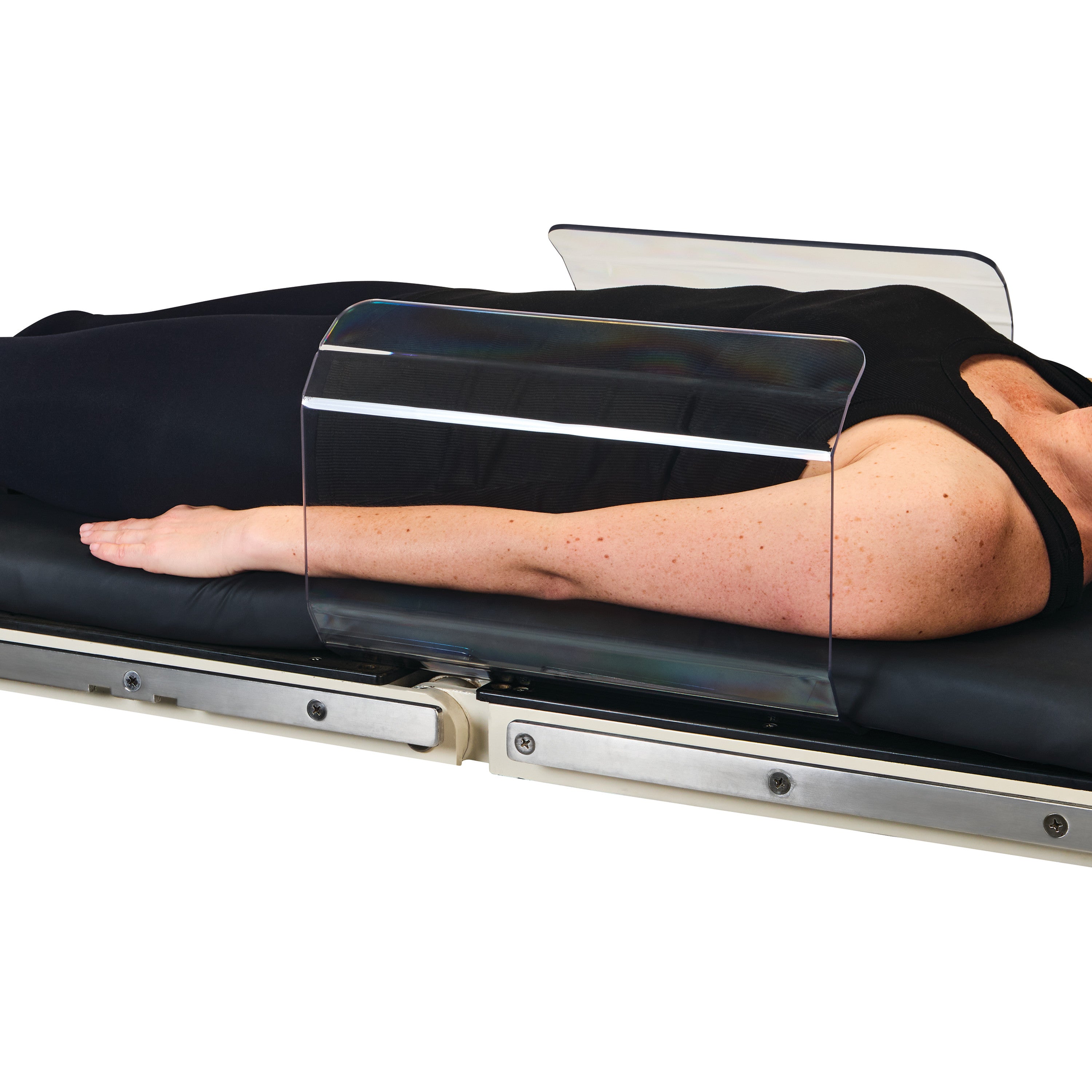 A person lies on a medical table with the AliMed Curved Toboggan Arm/Leg Guard securing their arm.