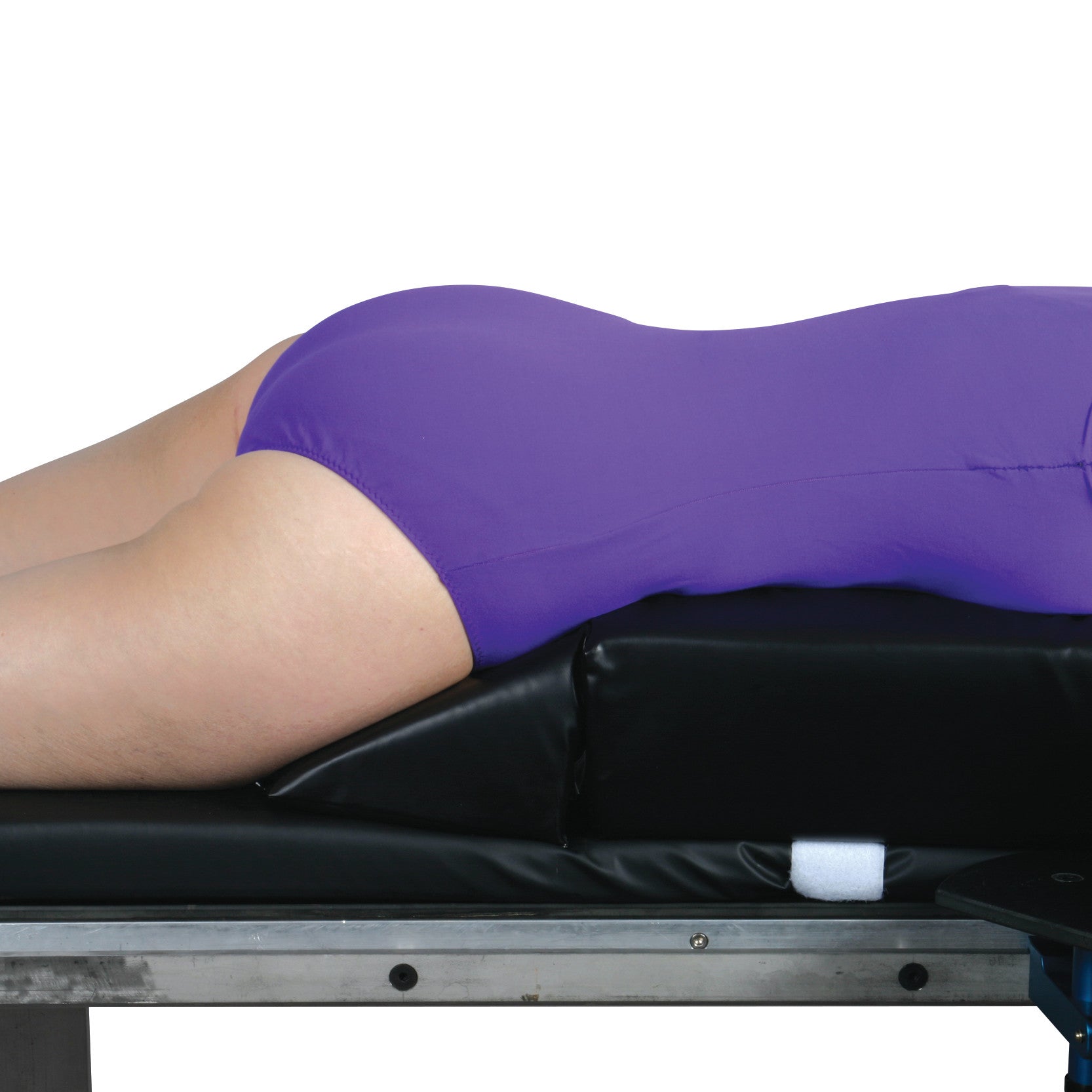 A person lies face down on the AliMed Vinyl-Covered Prone Lying System, which features a purple cover on a black cushion.