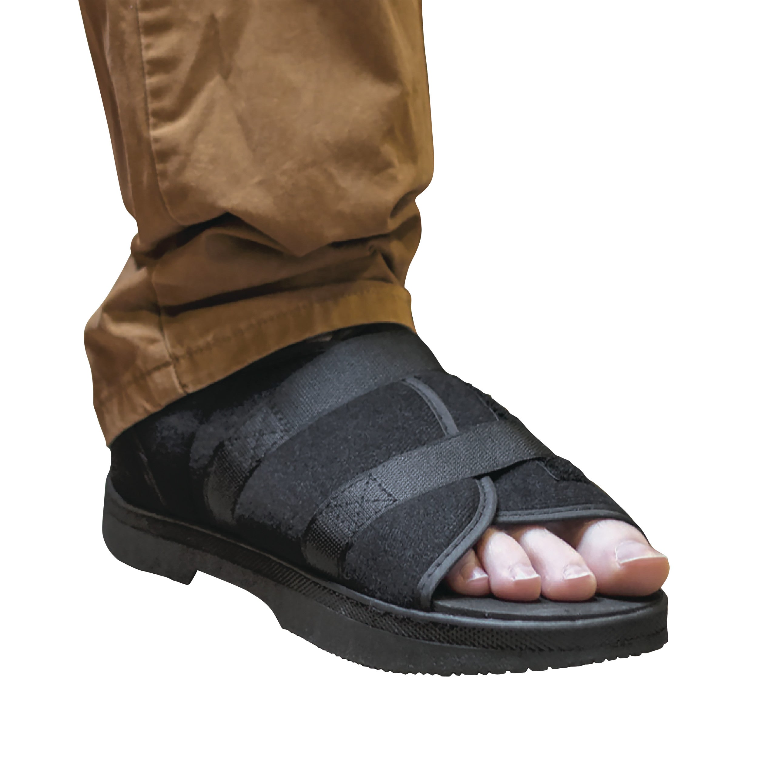 A foot wearing the DARCO Softie Shoe, an open-toed medical shoe with black adjustable straps, paired with brown pants.