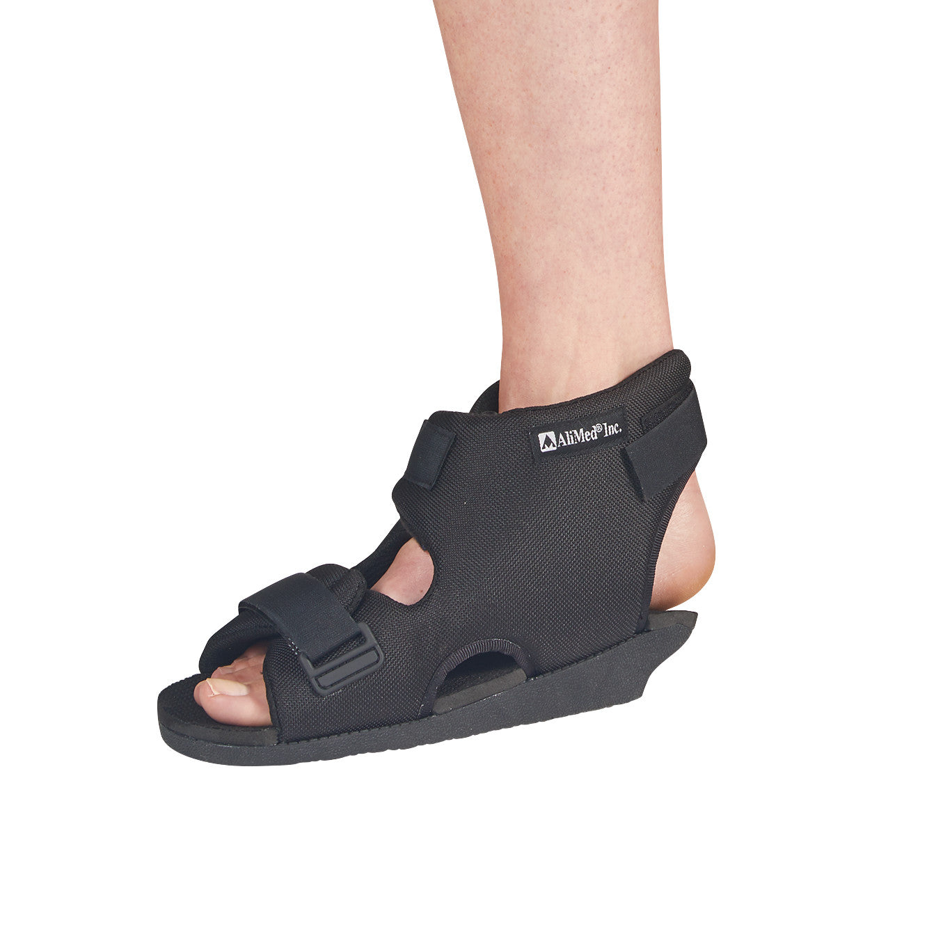 A person's foot wearing the AliMed Open Heel Orthosis, a black orthopedic shoe with straps and an open heel section.