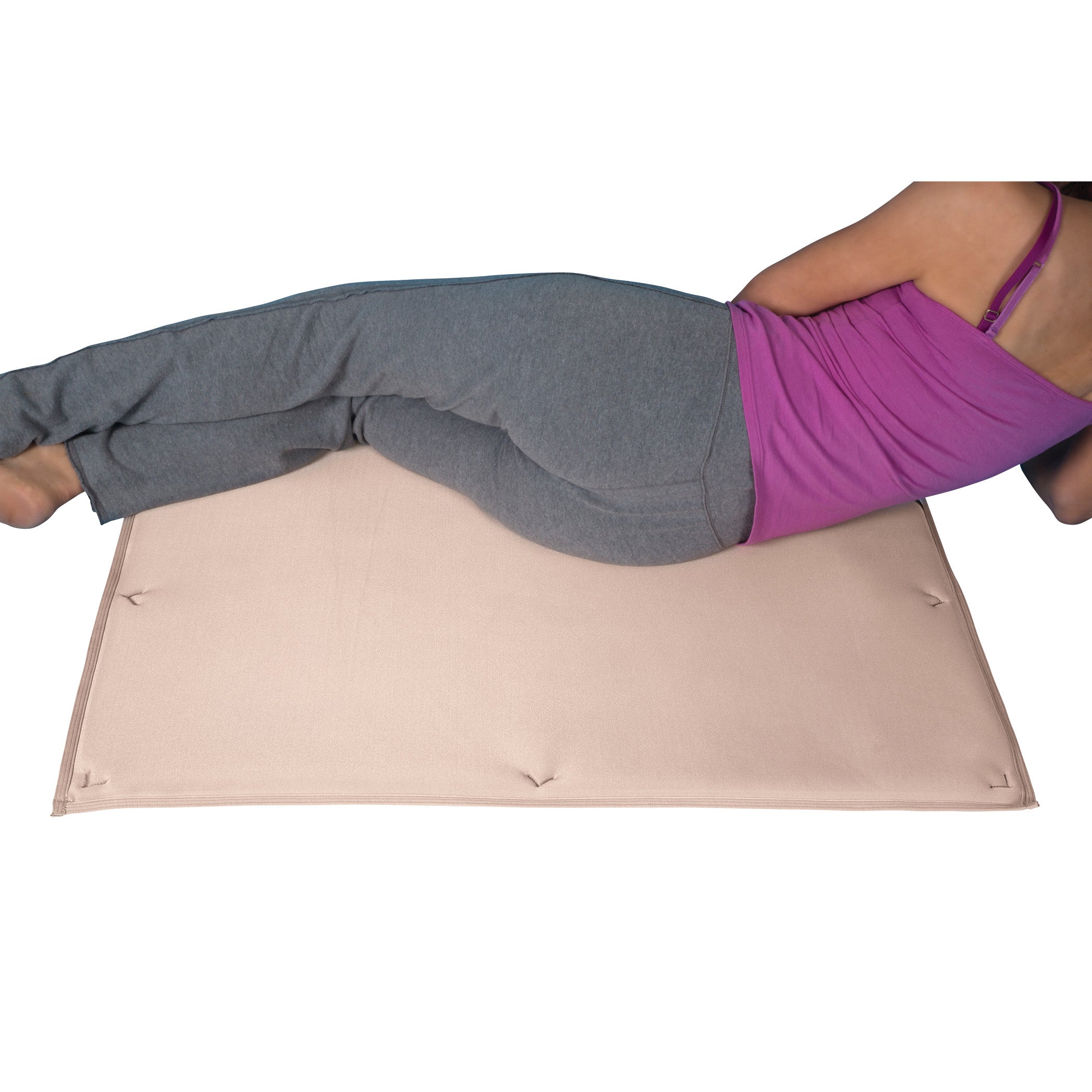 A person lies on a beige DermaSaver Pressure Reduction Pad, wearing gray pants and a purple top. The pad is on a flat surface.