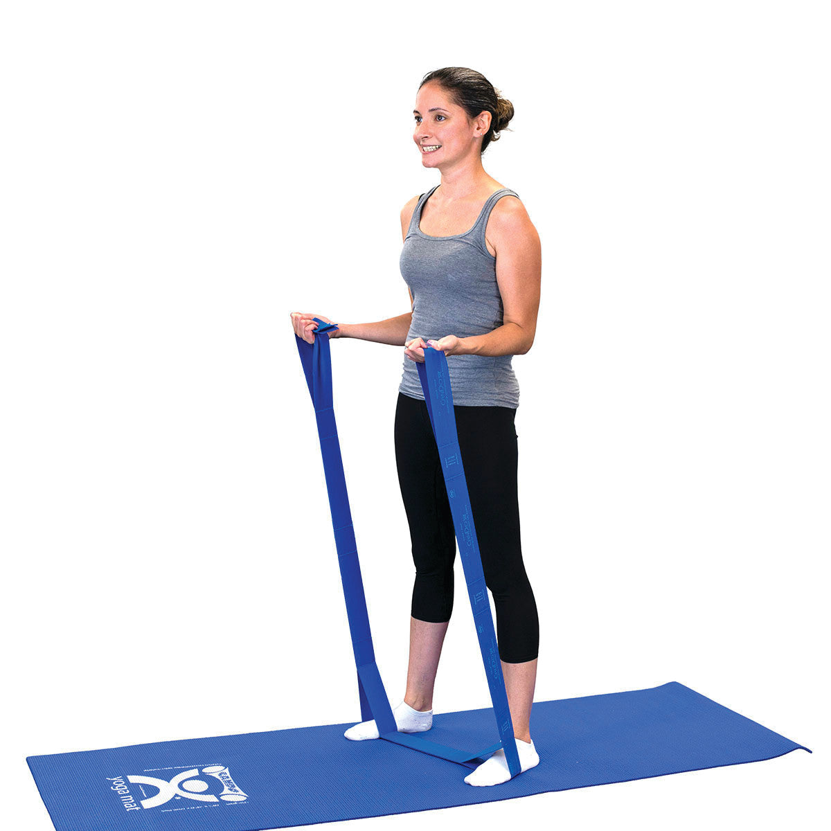 A woman stands on a blue mat using the blue CanDo Multi-Grip Exerciser, holding it with both hands for resistance training.