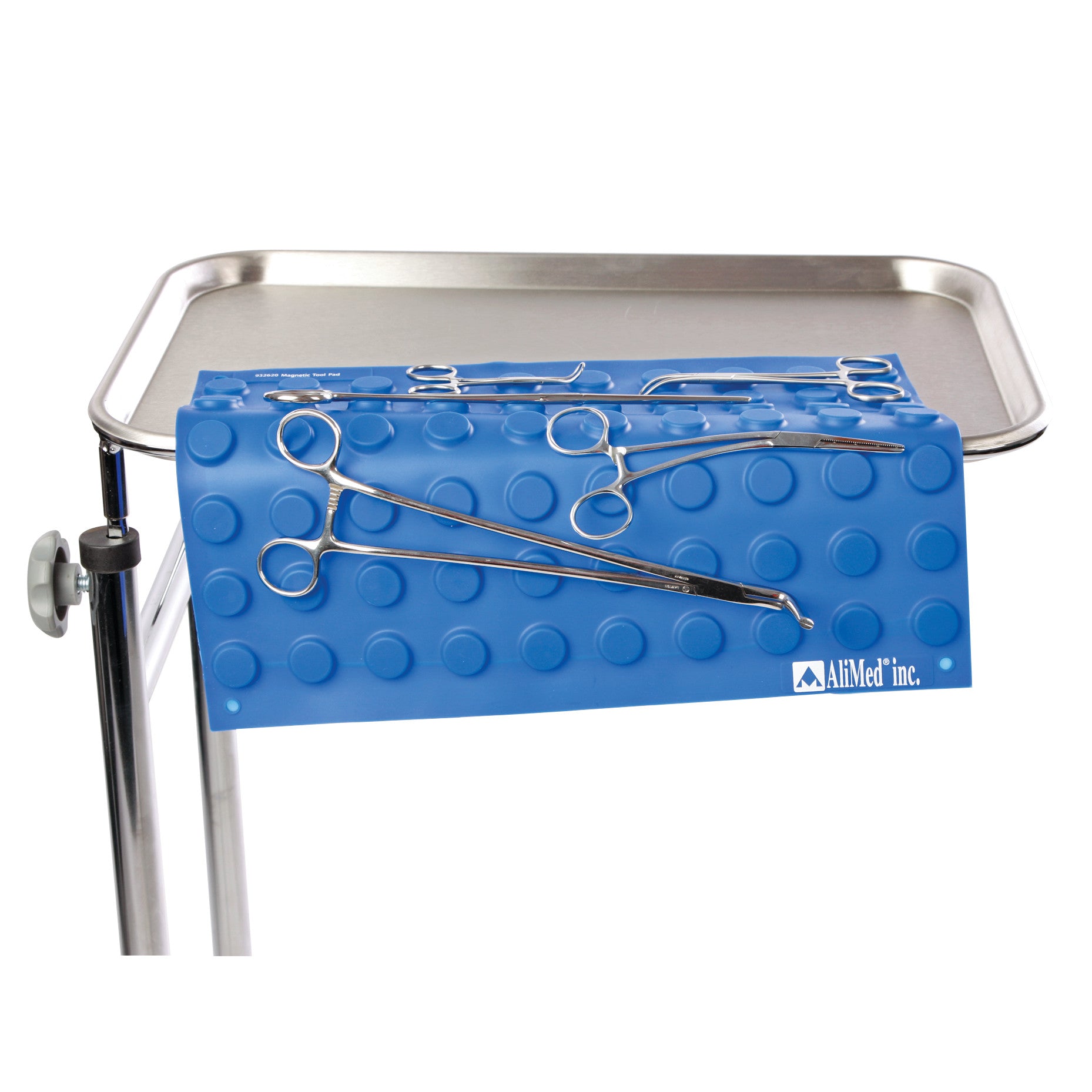 A blue AliMed Magnetic Instrument Pad with surgical tools on a stainless steel medical tray, featuring circular grip patterns.