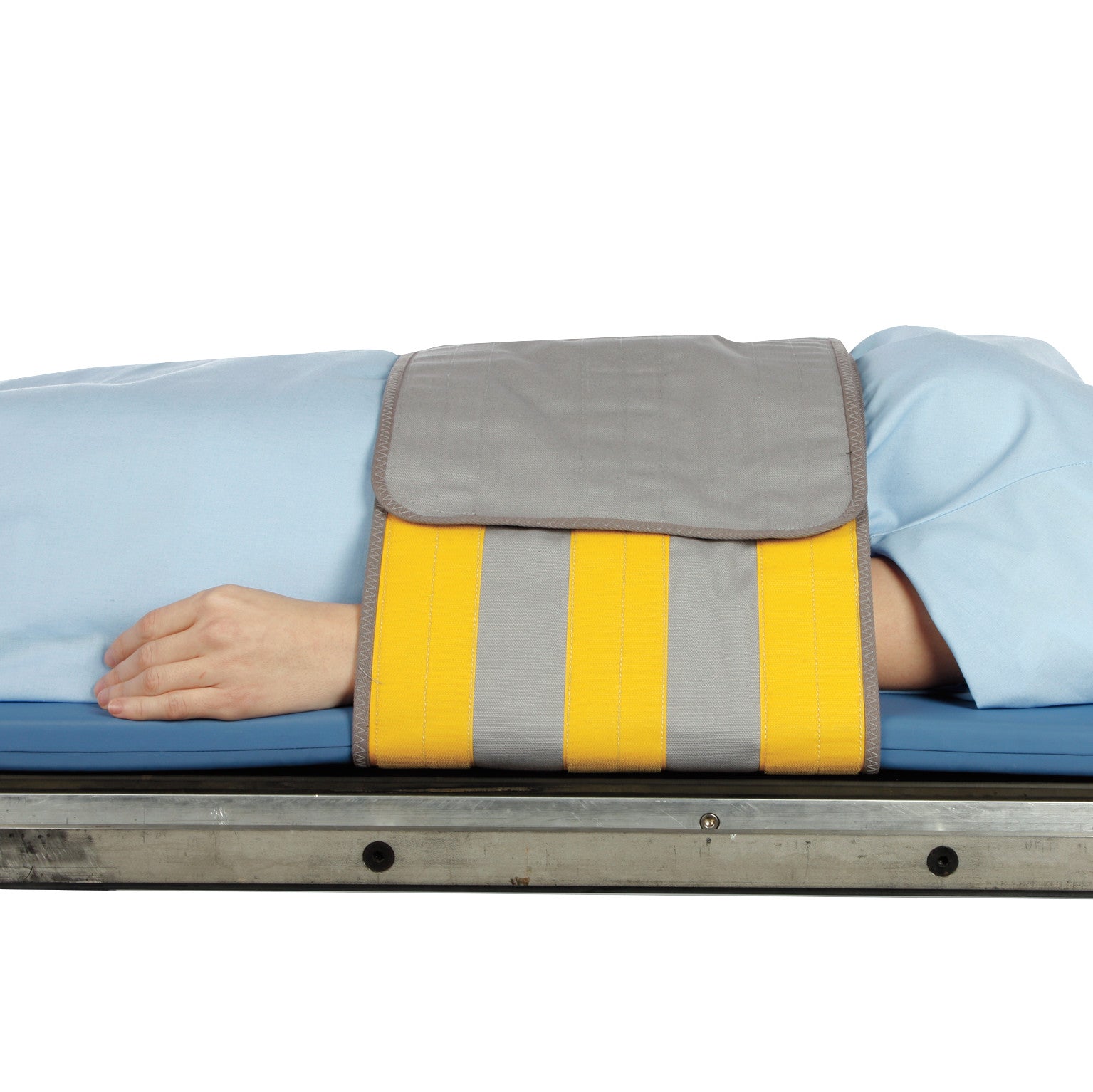 A person lies on a table with their abdomen restrained by the AliMed Radiolucent Abdominal Immobilizer with One Closure, featuring yellow stripes.