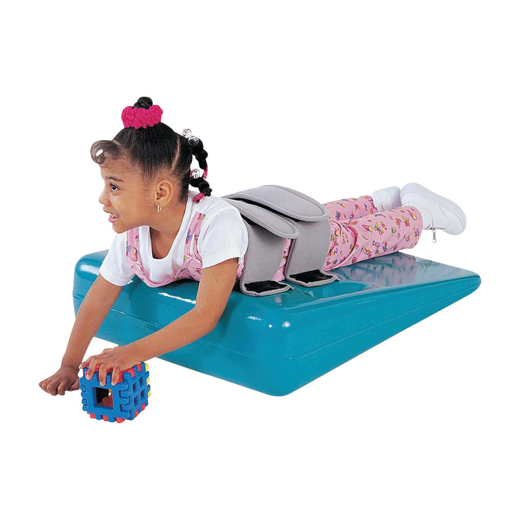 A child in pink overalls lies on the Tumble Forms2 12-1/2 Degree Deluxe Strap Wedge, holding a colorful toy block.