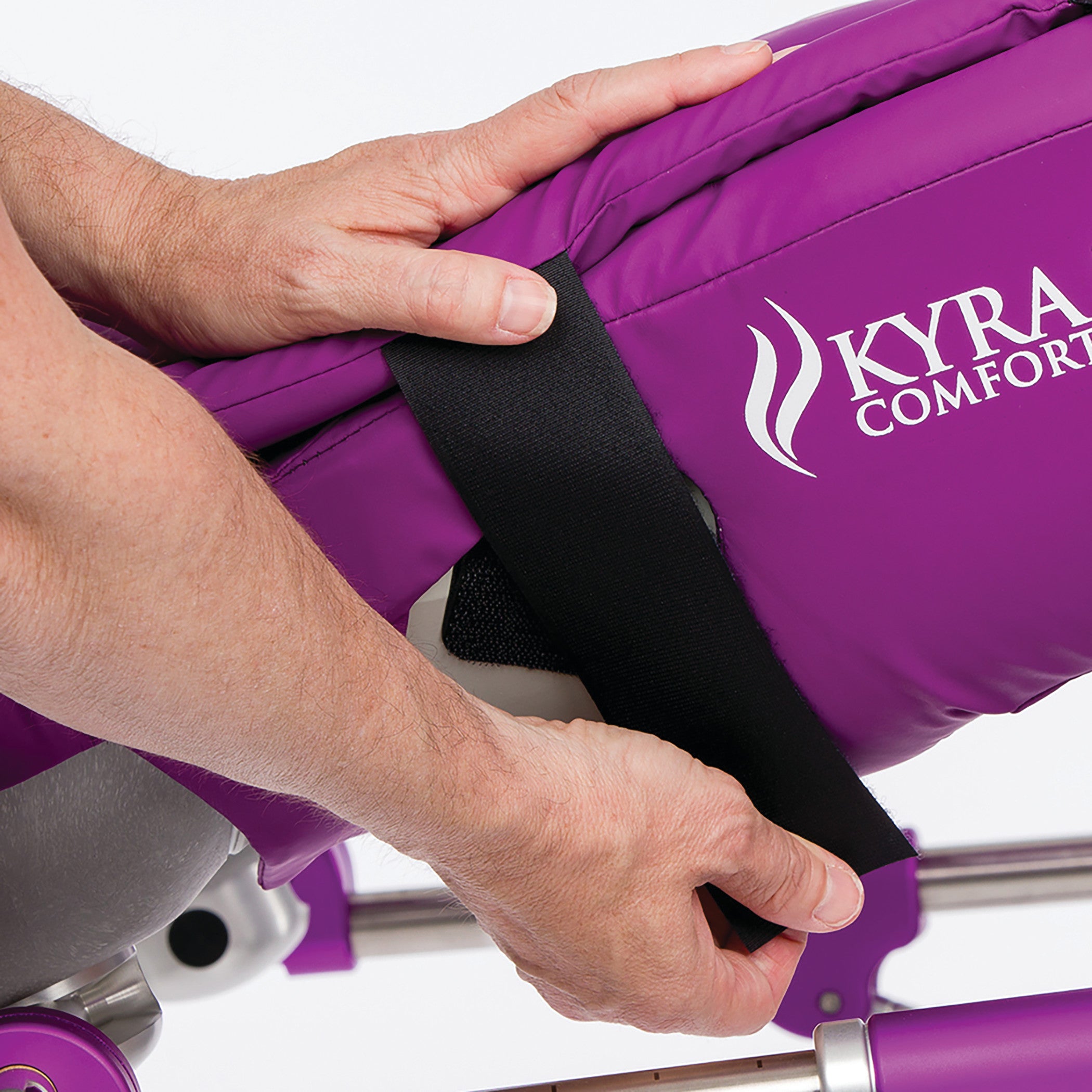 Hands adjust a KYRA Comfort 350 Lithotomy Stirrup, featuring a purple cushion and black hook-and-loop straps.
