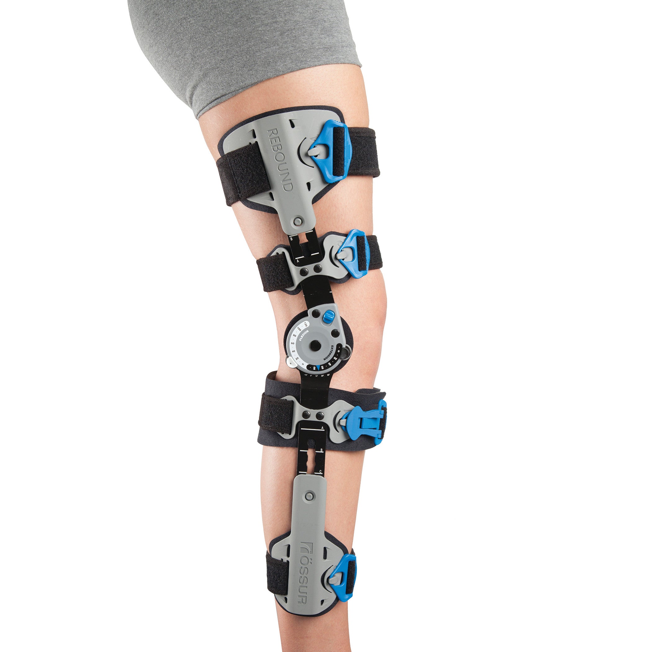 A person wears the Ossur Rebound Post-Op Knee Brace with Cool Liner. The brace has adjustable straps and a dial for customization.