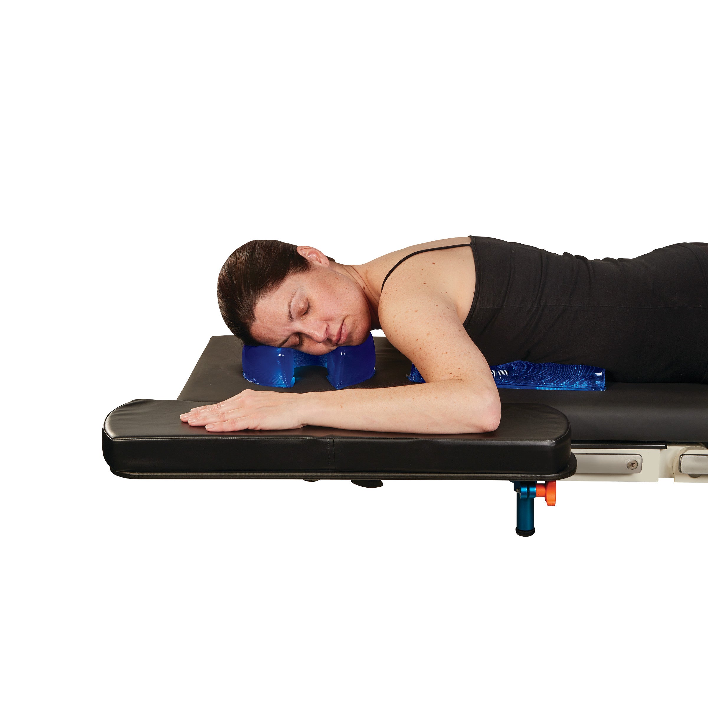 A woman lies face down on a black table, using the AliMed AliBlue Gel Horseshoe Donut for neck support.