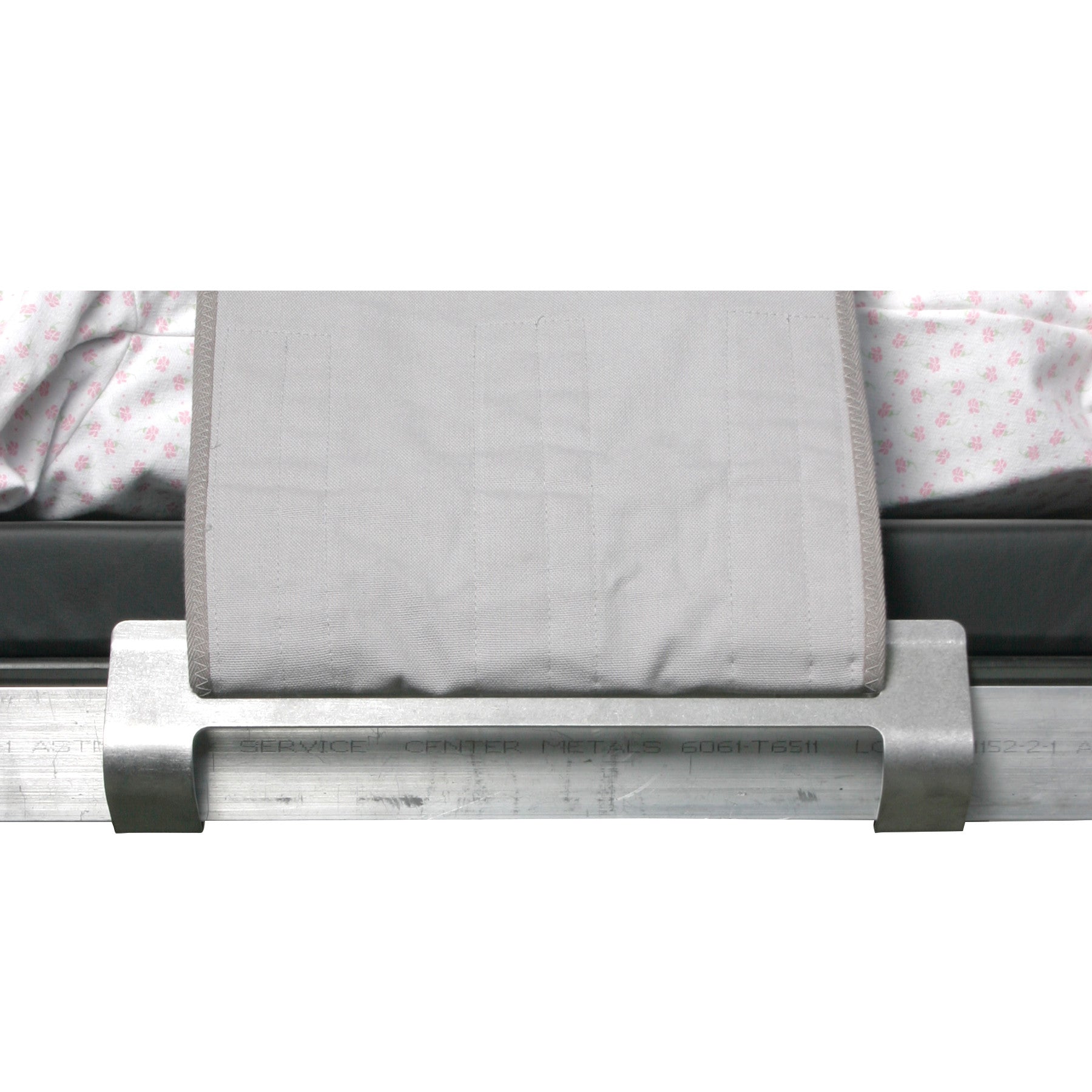 AliMed Grabber Bracket secures a light gray strap onto a hospital bed with floral-patterned sheets on a mattress base.