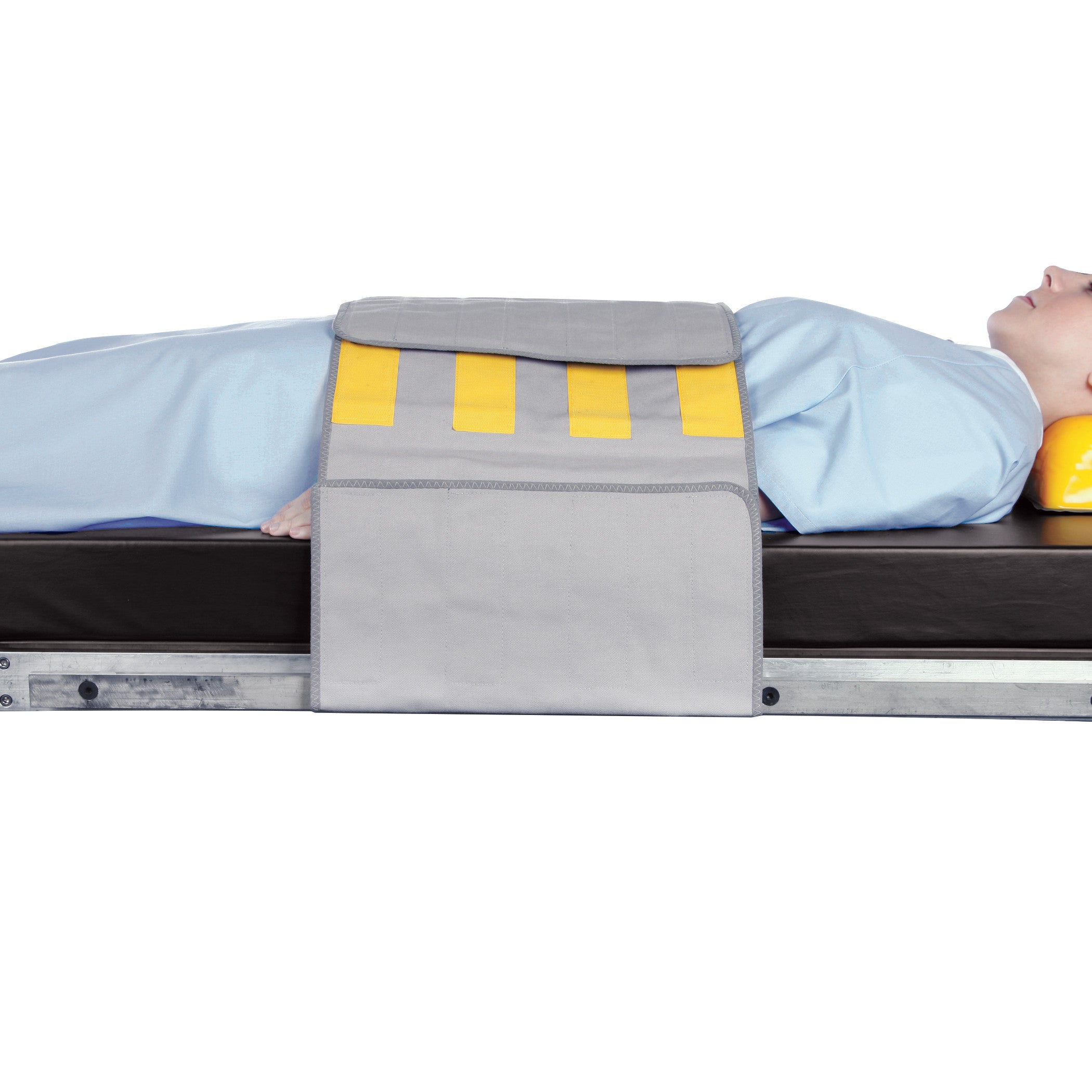 Person lying under an AliMed Radiolucent Abdominal Immobilizer with Three Closures, shown on a medical table.